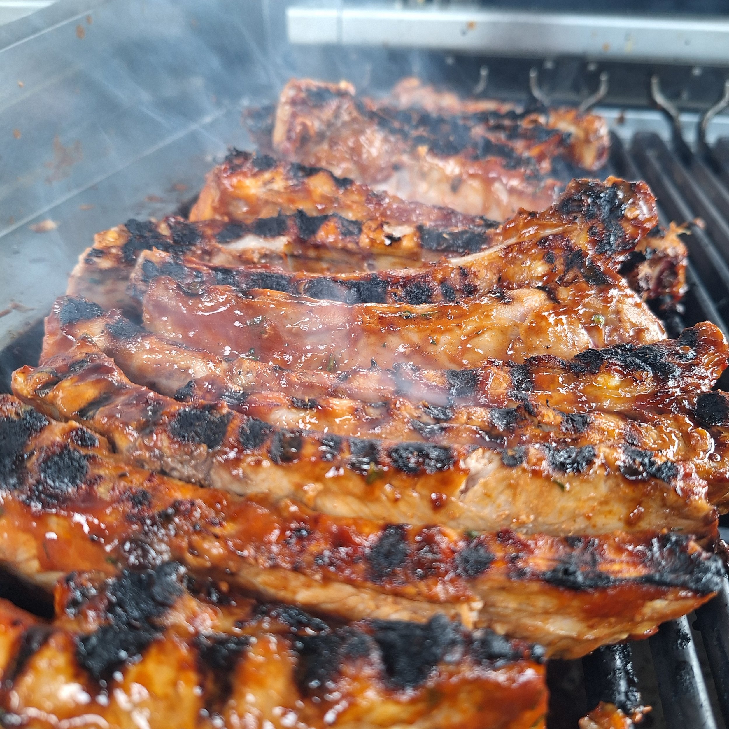 Barbecued pork ribs on a grill with charred grill marks and smoky glaze.