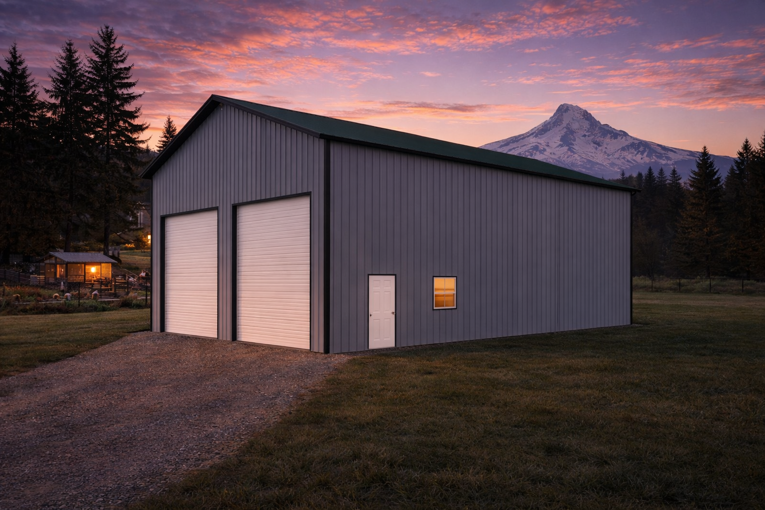 A gray metal building with two large garage doors, a small door, and a window, set on a grassy lot at sunset with Mount Hood in the background and trees surrounding the area.