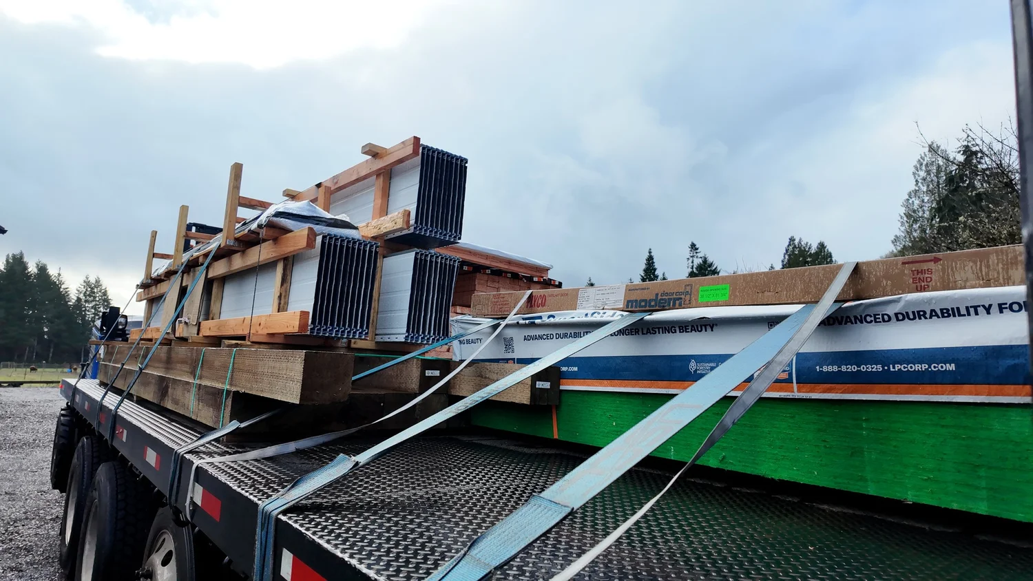 Flatbed delivery truck hauling a pole barn kit package