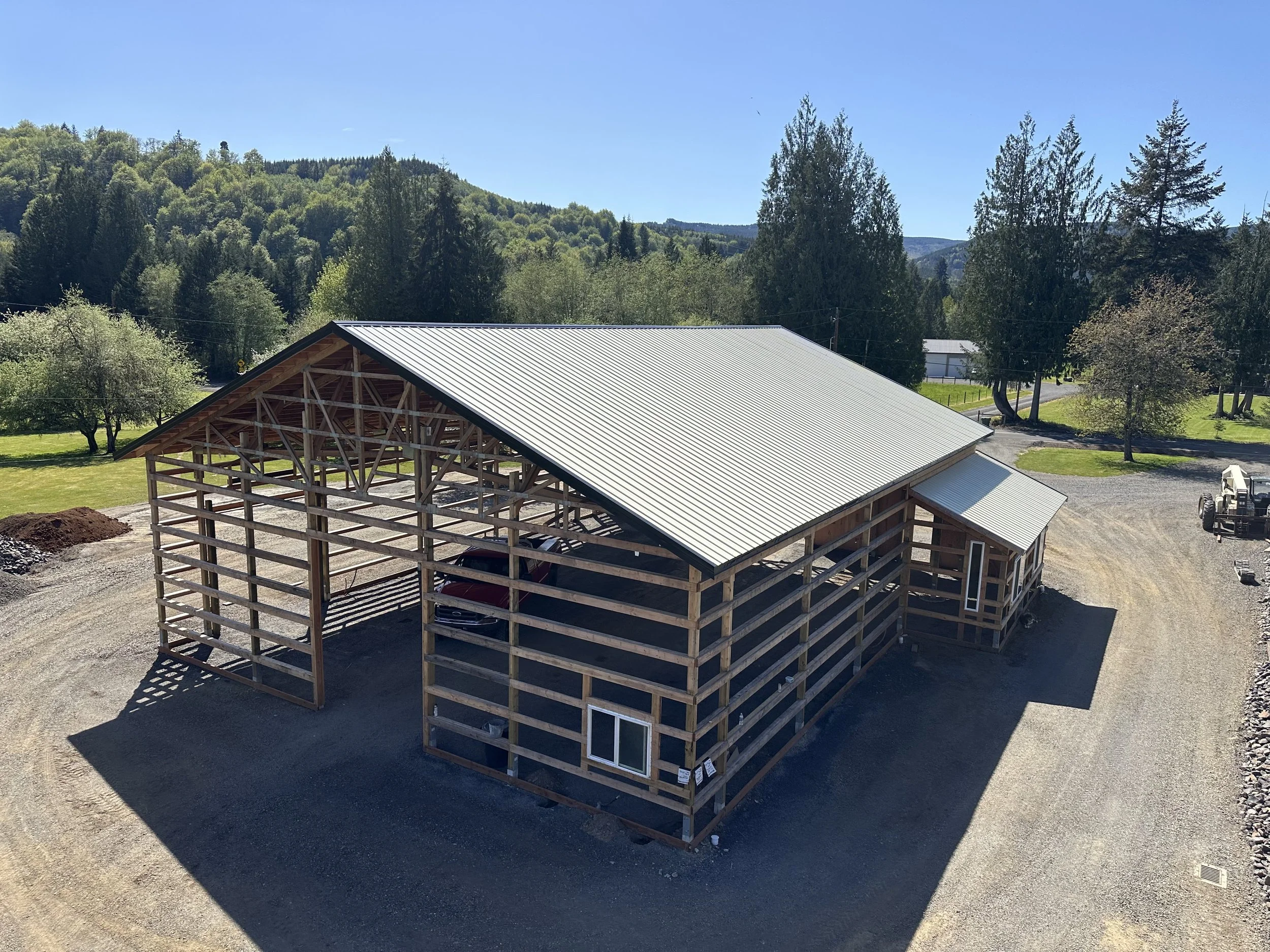 Columbia Structure post-frame structure under construction with treated posts and an engineered metal roof frame in Southwest Washington