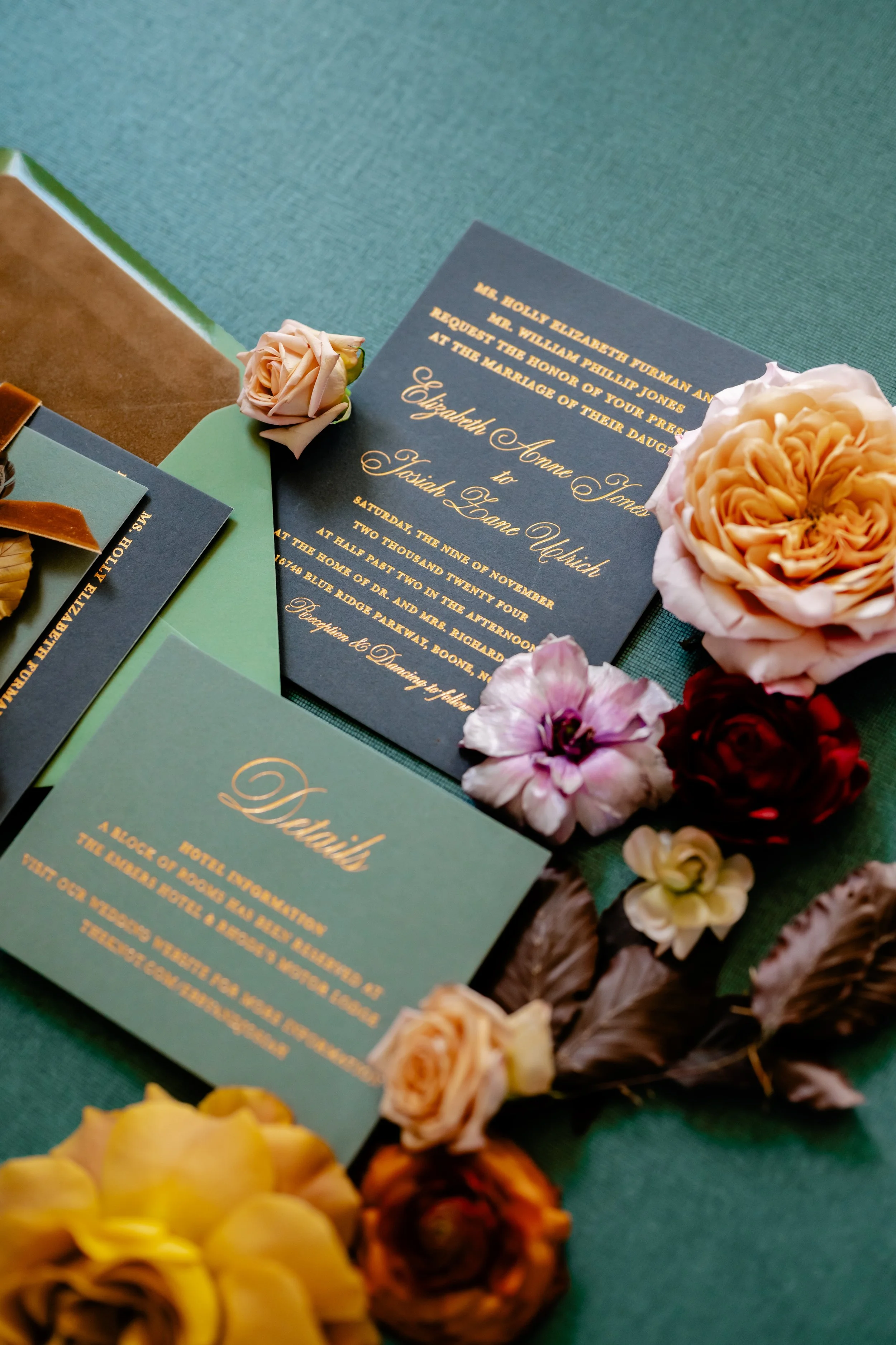 Wedding invitation card with floral decorations on a green table.