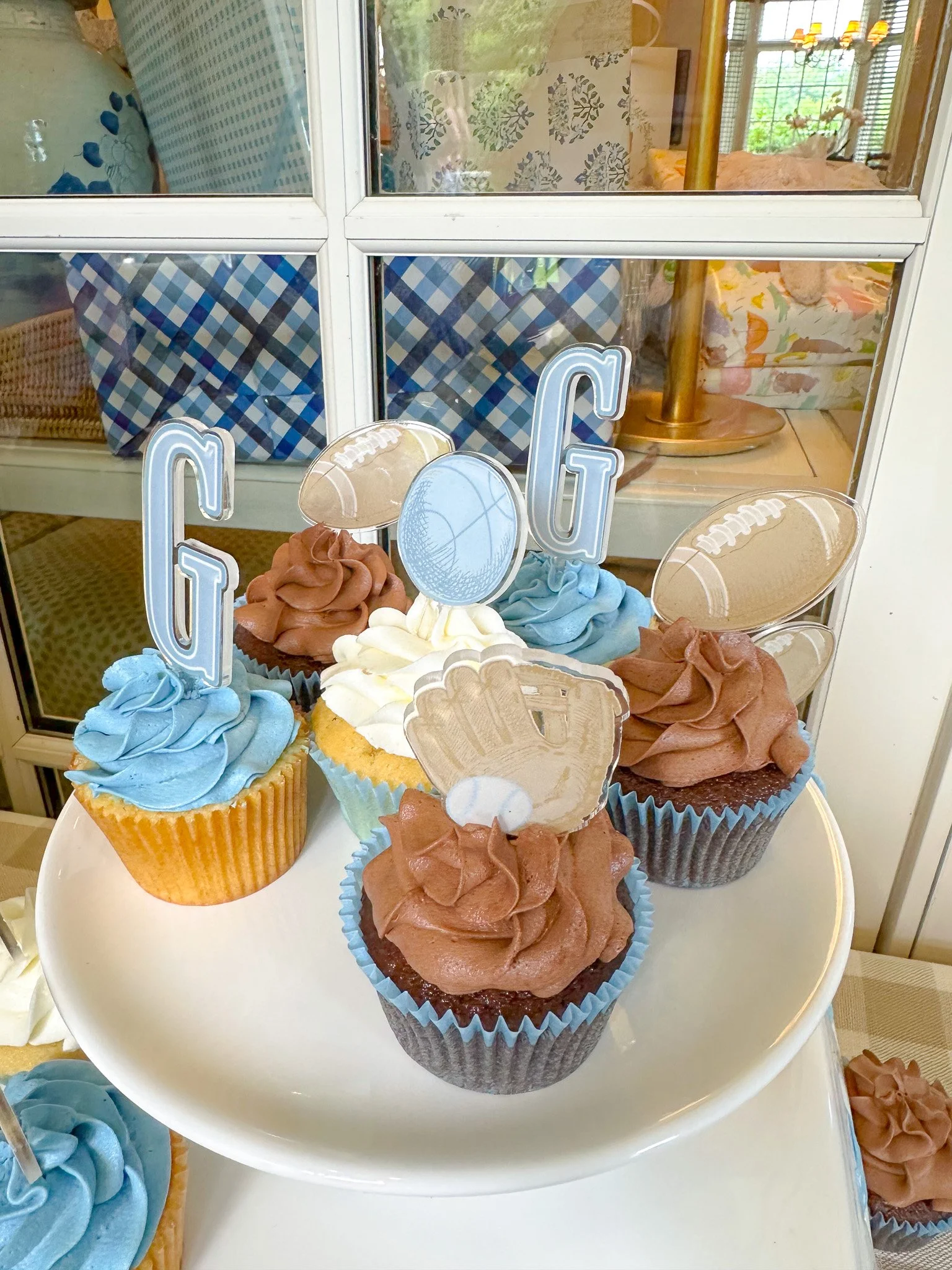 Cupcakes with blue and brown frosting decorated with football-themed toppers on a white plate.