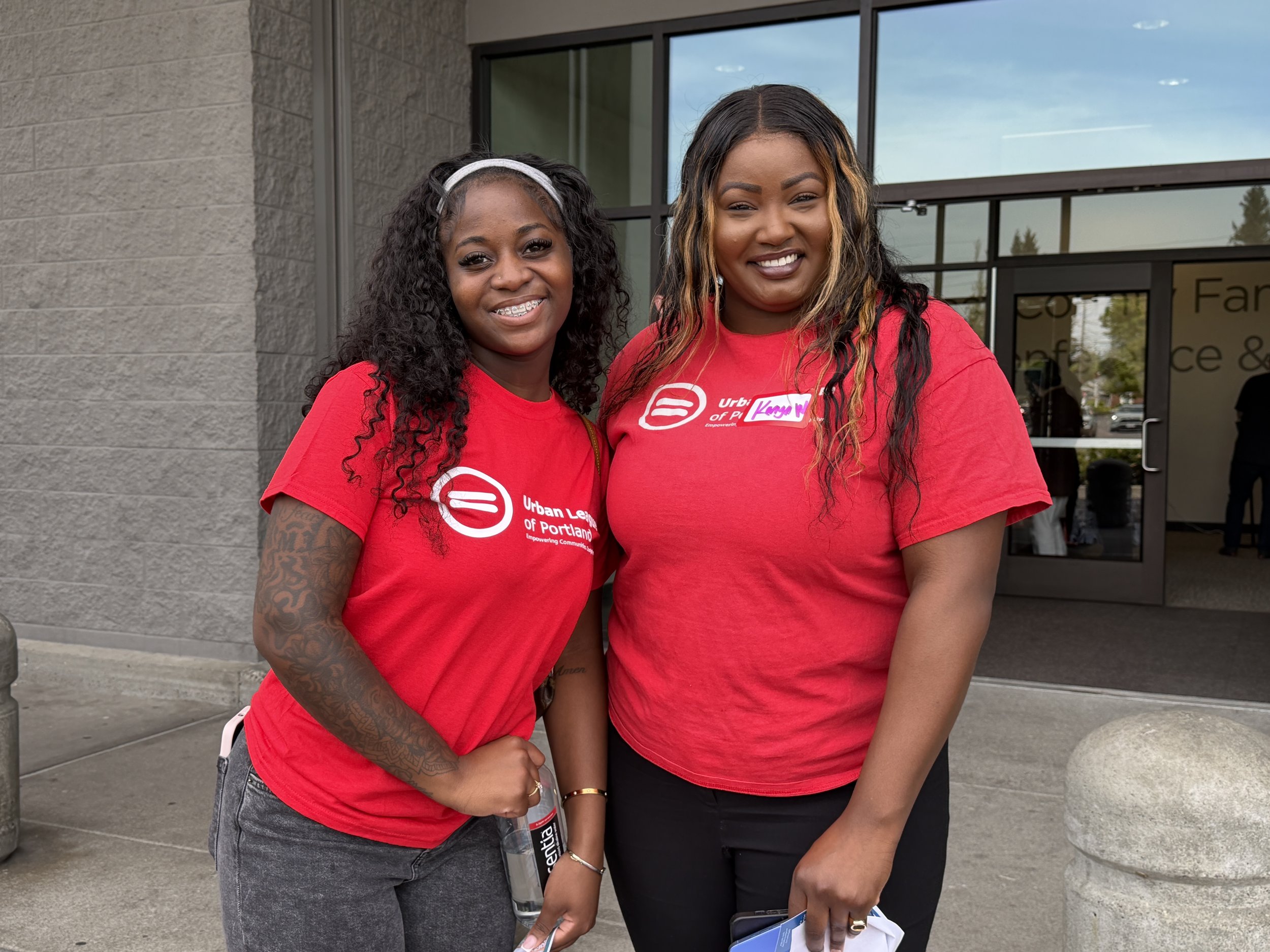 Two women in red Urban League t-shirts smiling