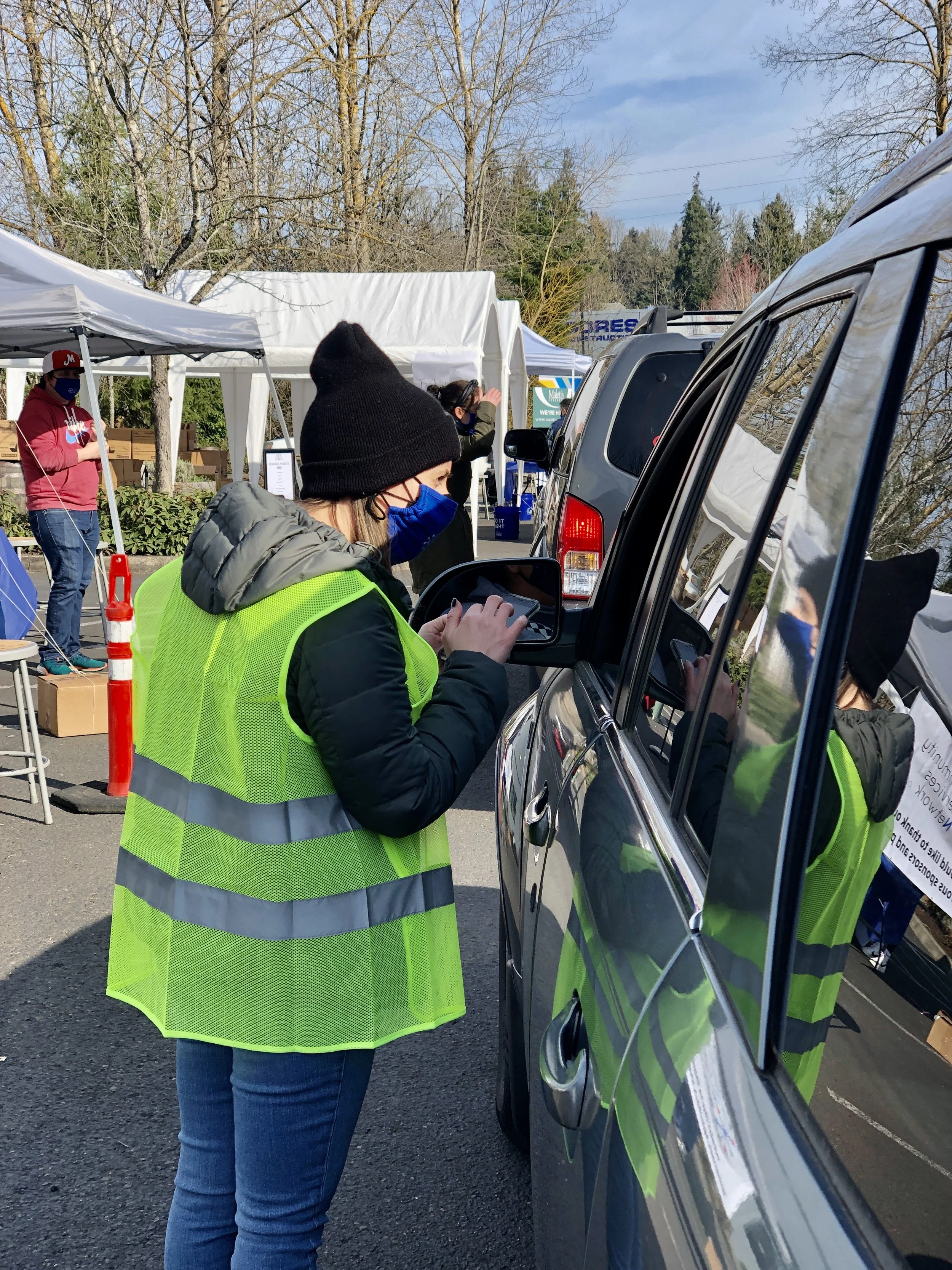  A volunteer in a yellow safety vest assists a community member at a drive-through CSN community resource fair in Portland, Oregon. 