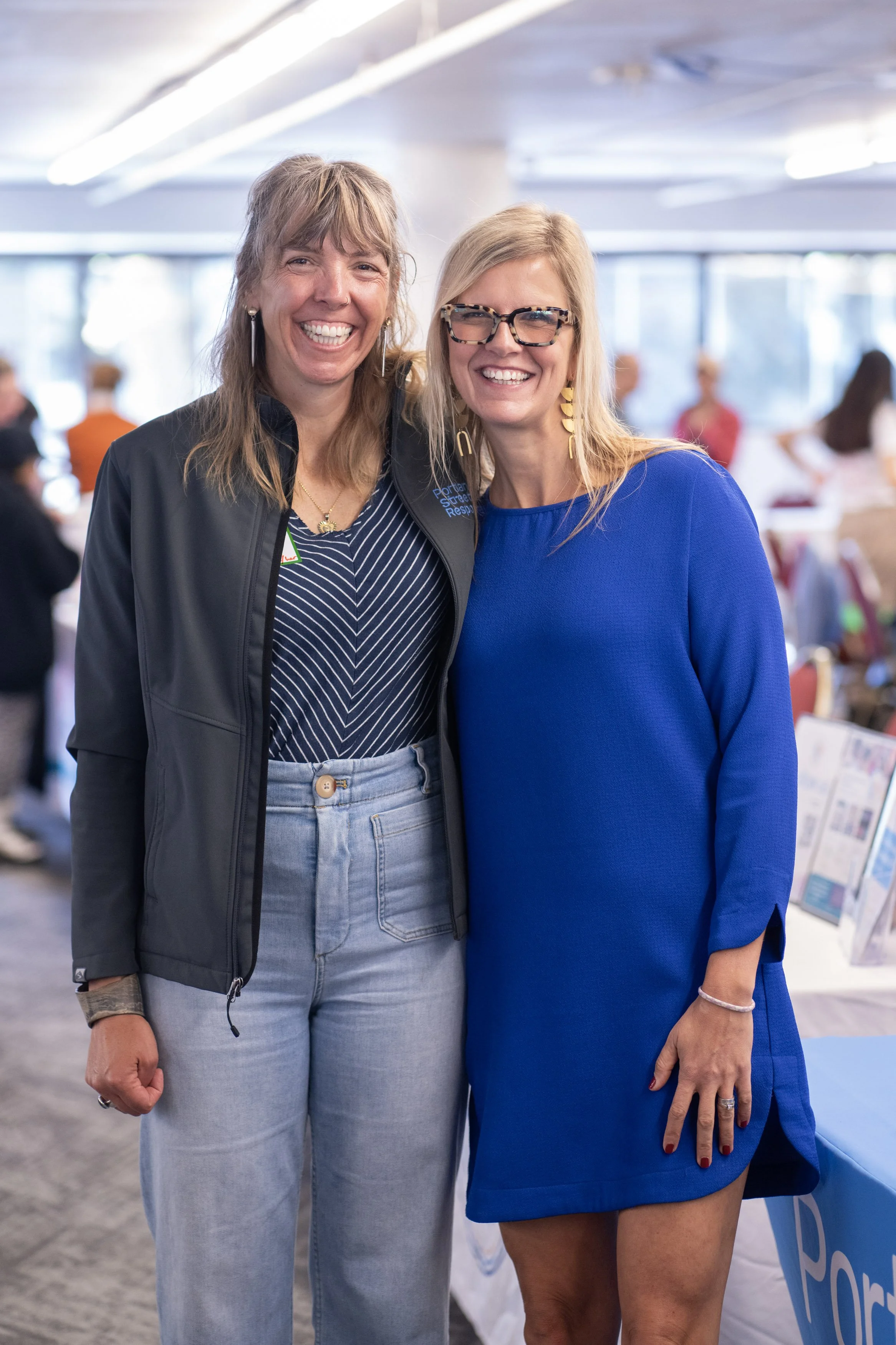  Two women smiling together at an indoor CSN Nonprofit Connect networking event in Portland, Oregon. 