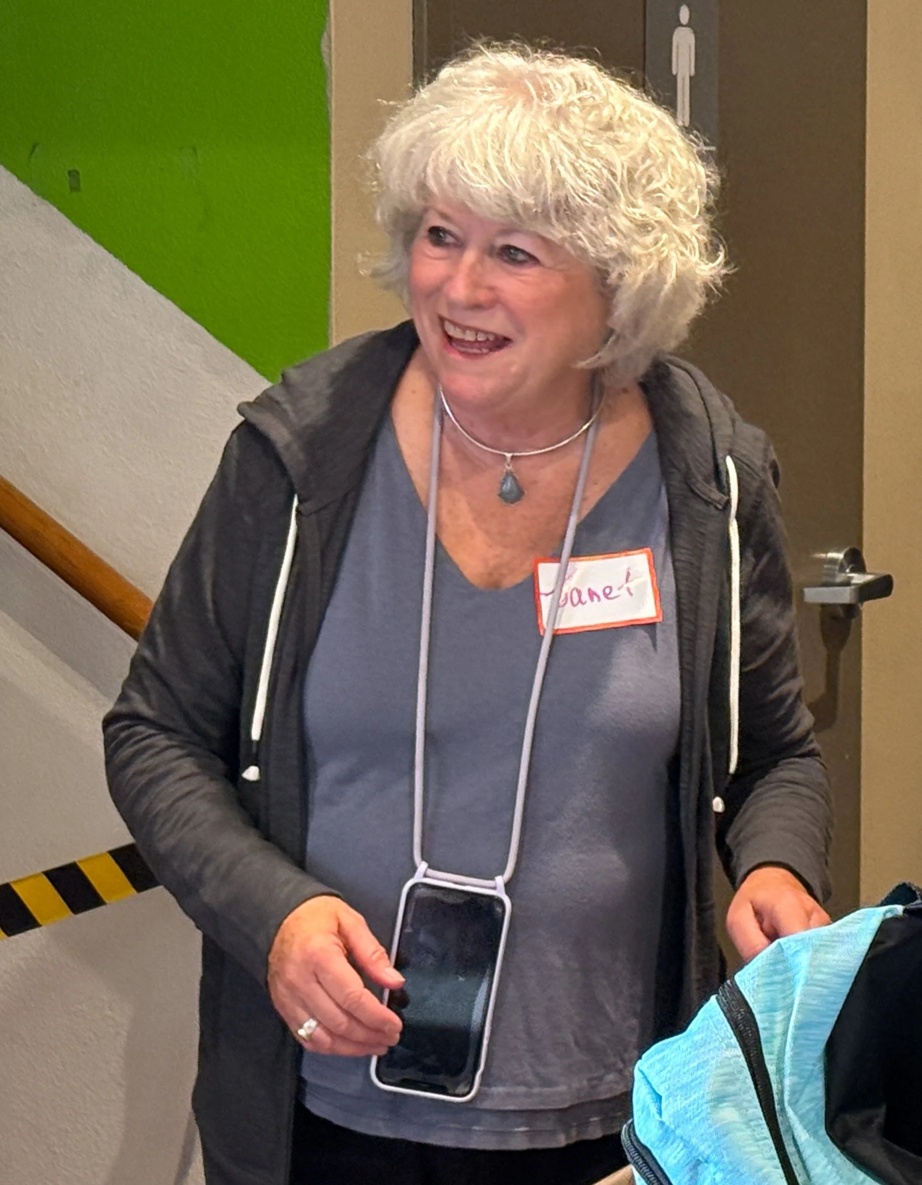  A CSN volunteer smiling warmly while helping at a community event, wearing a name tag at a CSN resource fair in Portland, Oregon. 