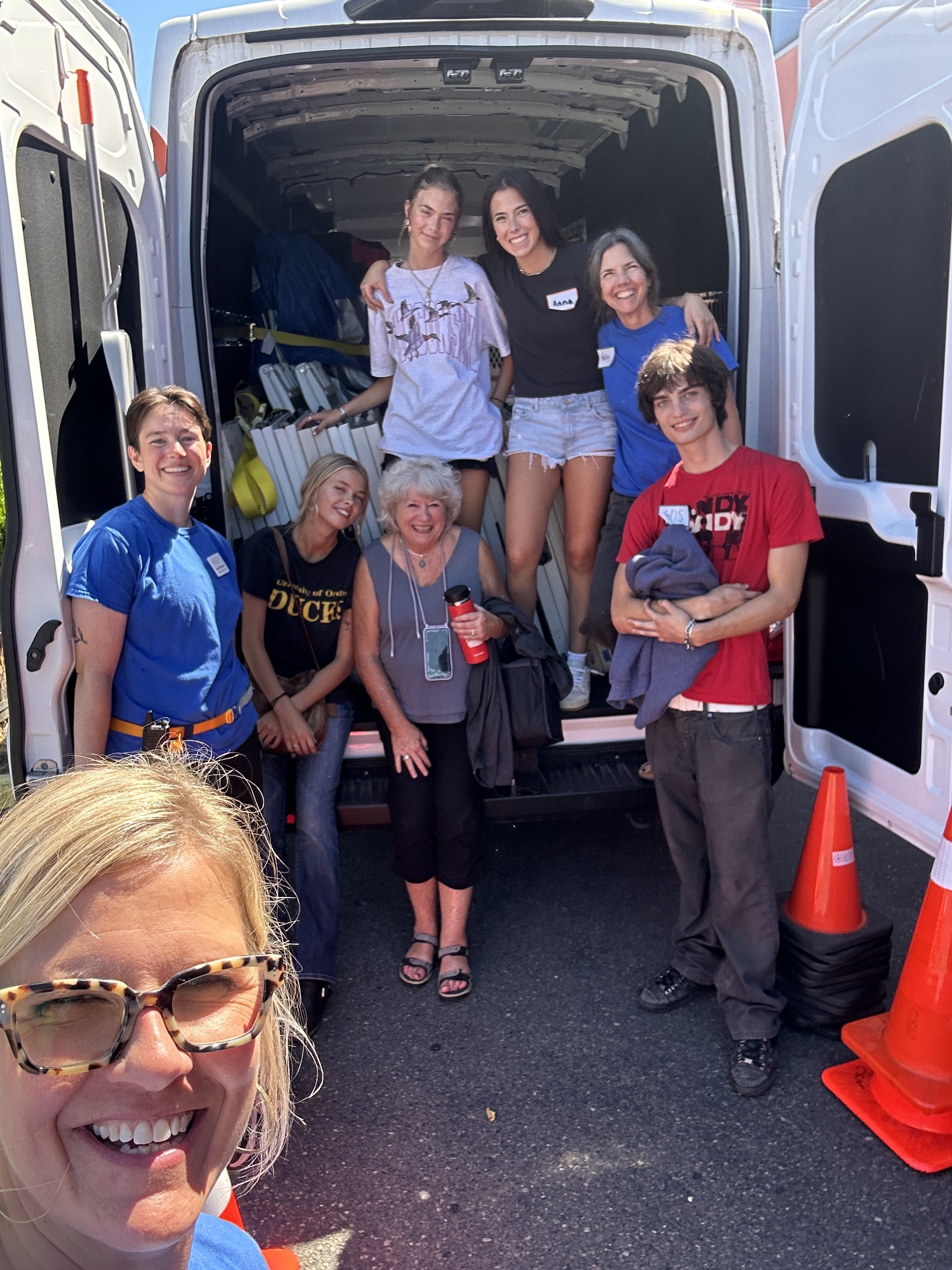  A group of CSN volunteers gathered near a van at an outdoor community resource fair, preparing to deliver services in Portland, Oregon. 