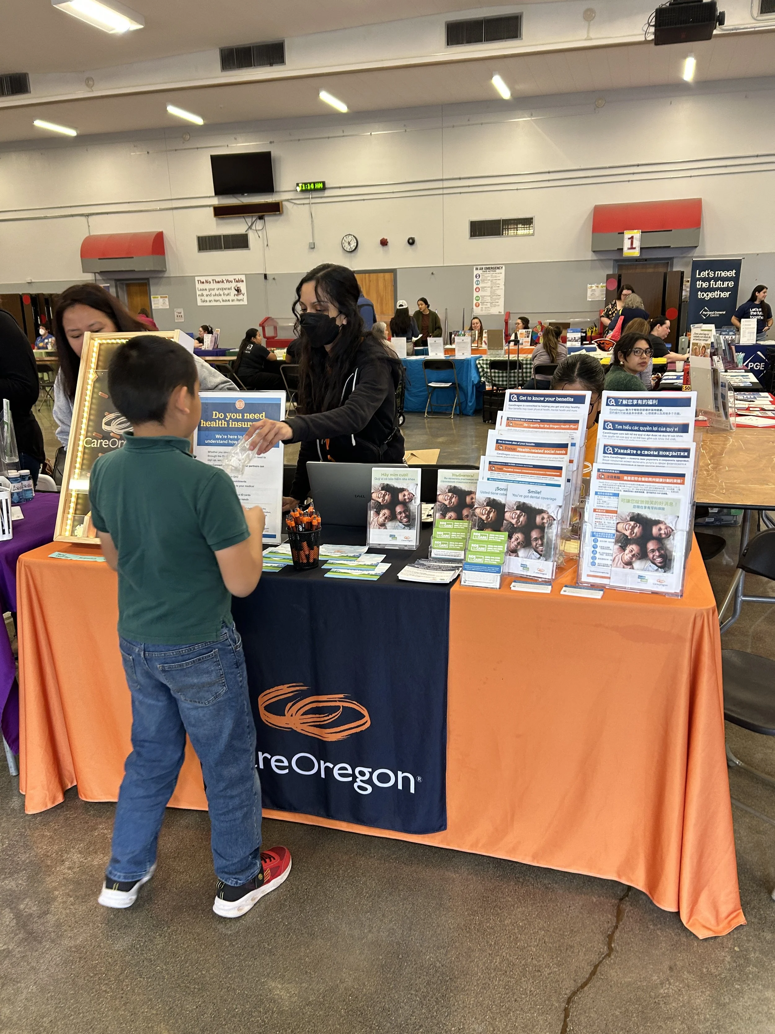  A community member reviewing health insurance materials at a CareOregon sponsor booth during a CSN community resource fair in Portland, Oregon. 