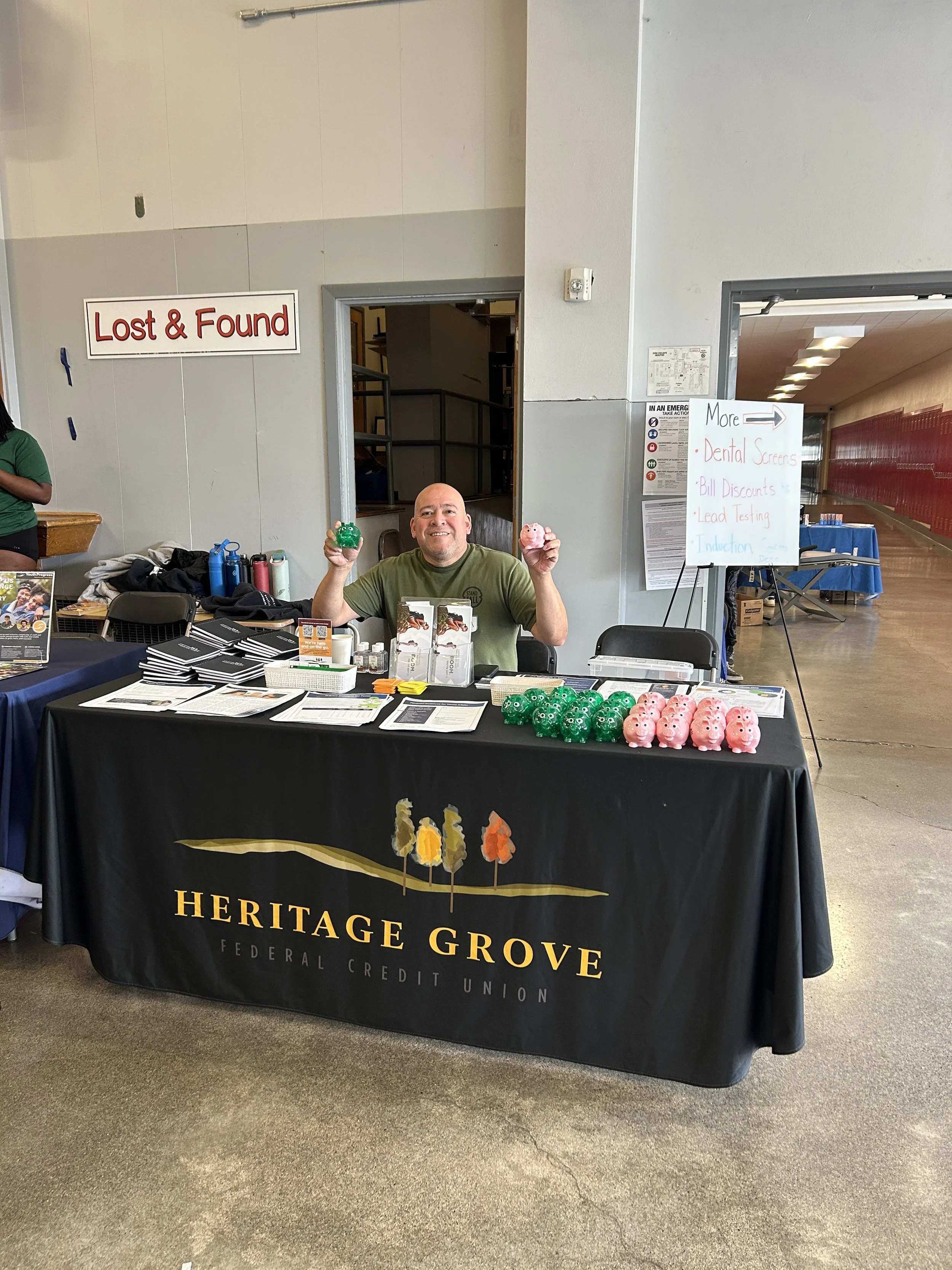  A Heritage Grove Federal Credit Union representative staffing a sponsor booth with giveaway items at a CSN community resource fair. 