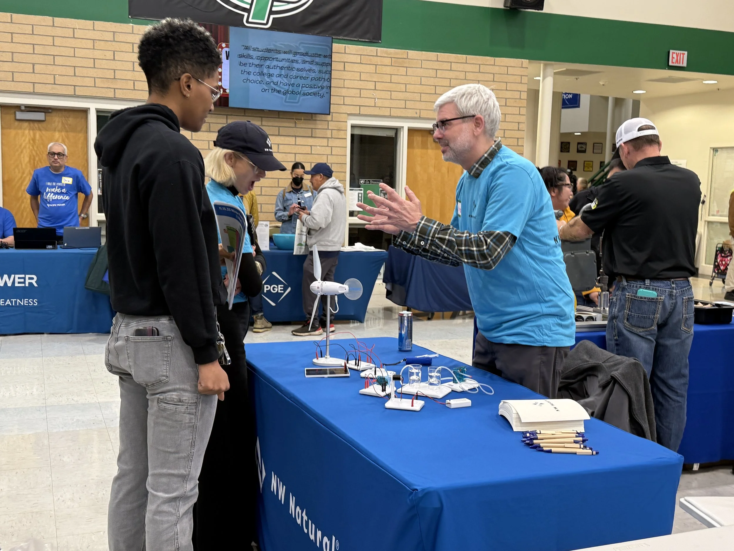  A Northwest Natural representative speaking to young community members at an indoor CSN community resource fair. 