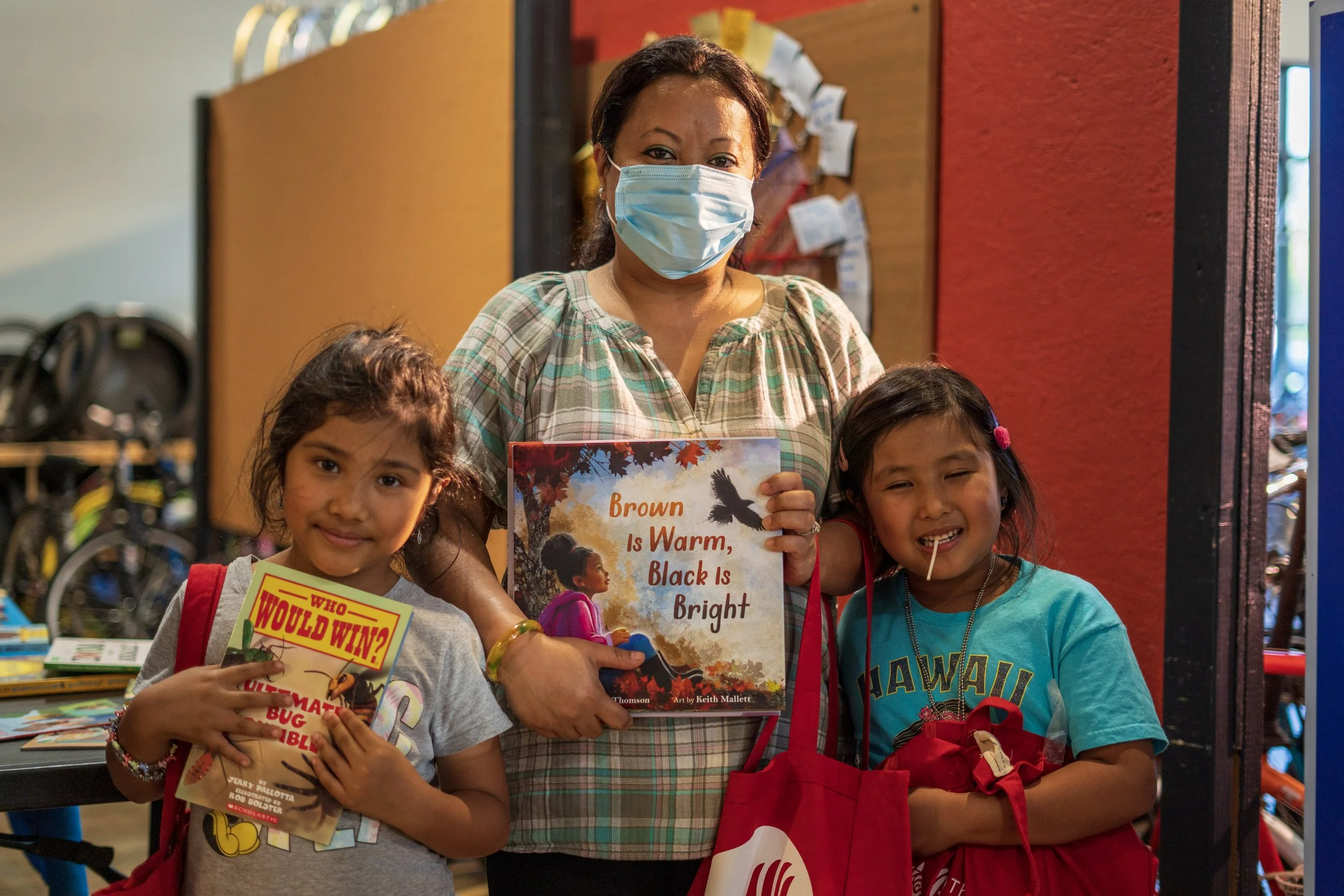 Woman and two young children with books at Community Resource Fair