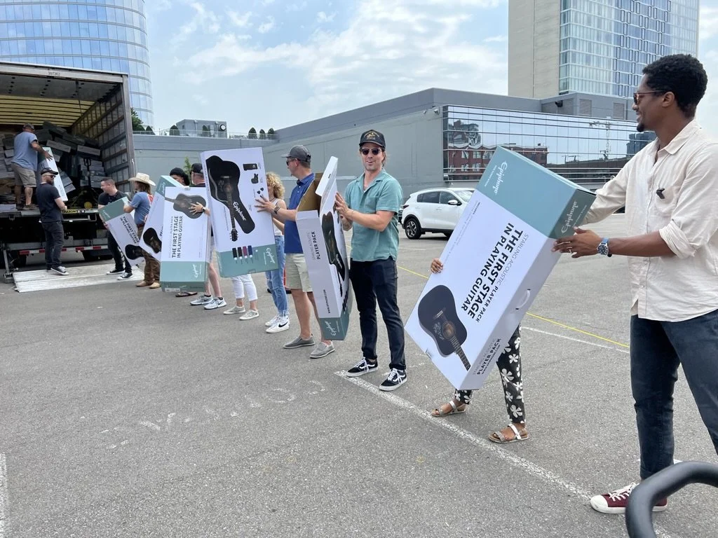 Group unloading boxes from truck during Free Guitars 4 Kids event