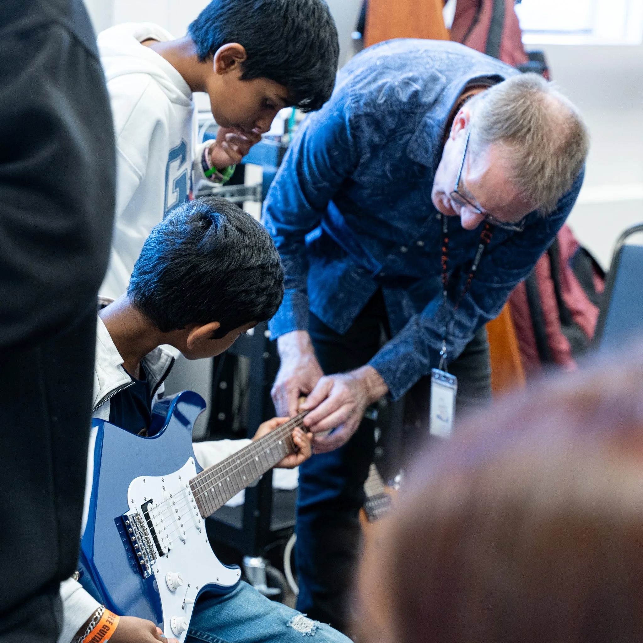 Close-up of a pink electric guitar with chrome tuning pegs and pickups, slightly out of focus in the background.