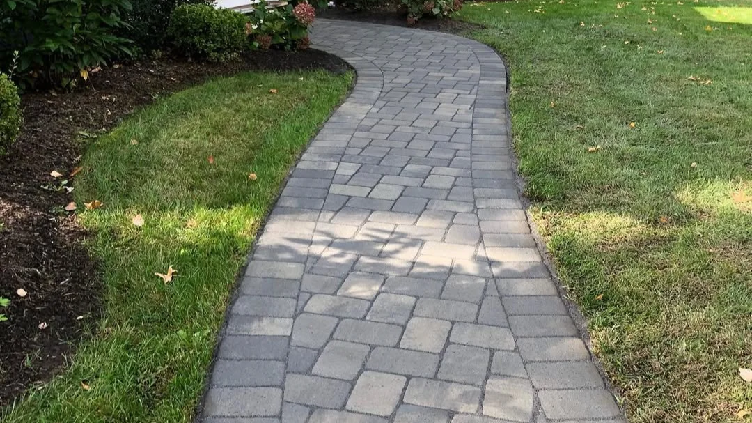 A curved stone pathway bordered by green grass and shrubs.