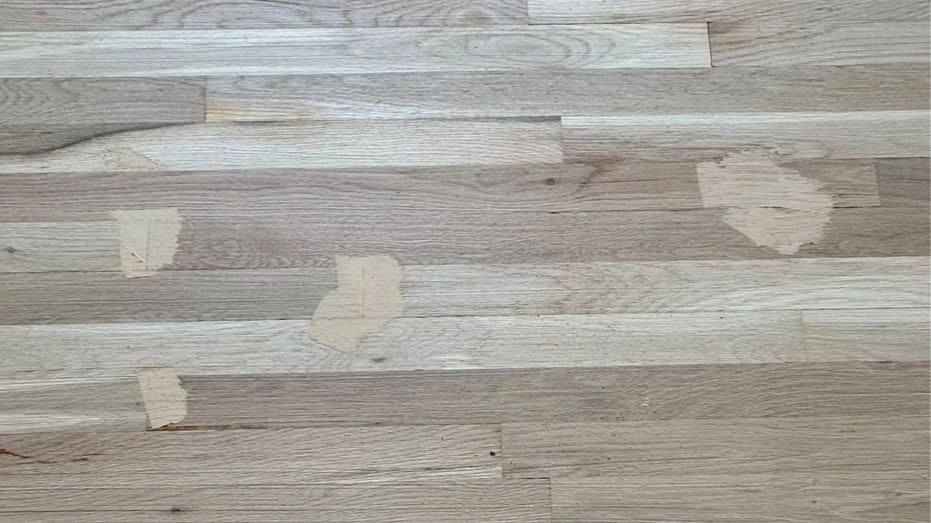 Wooden floor with patches of peeling paint or tape.