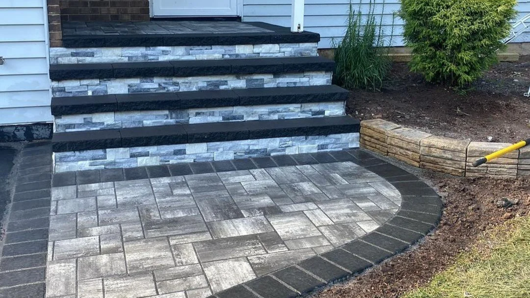 Newly landscaped front porch with stone stairs, a paver walkway, and a flower bed with wood edging.