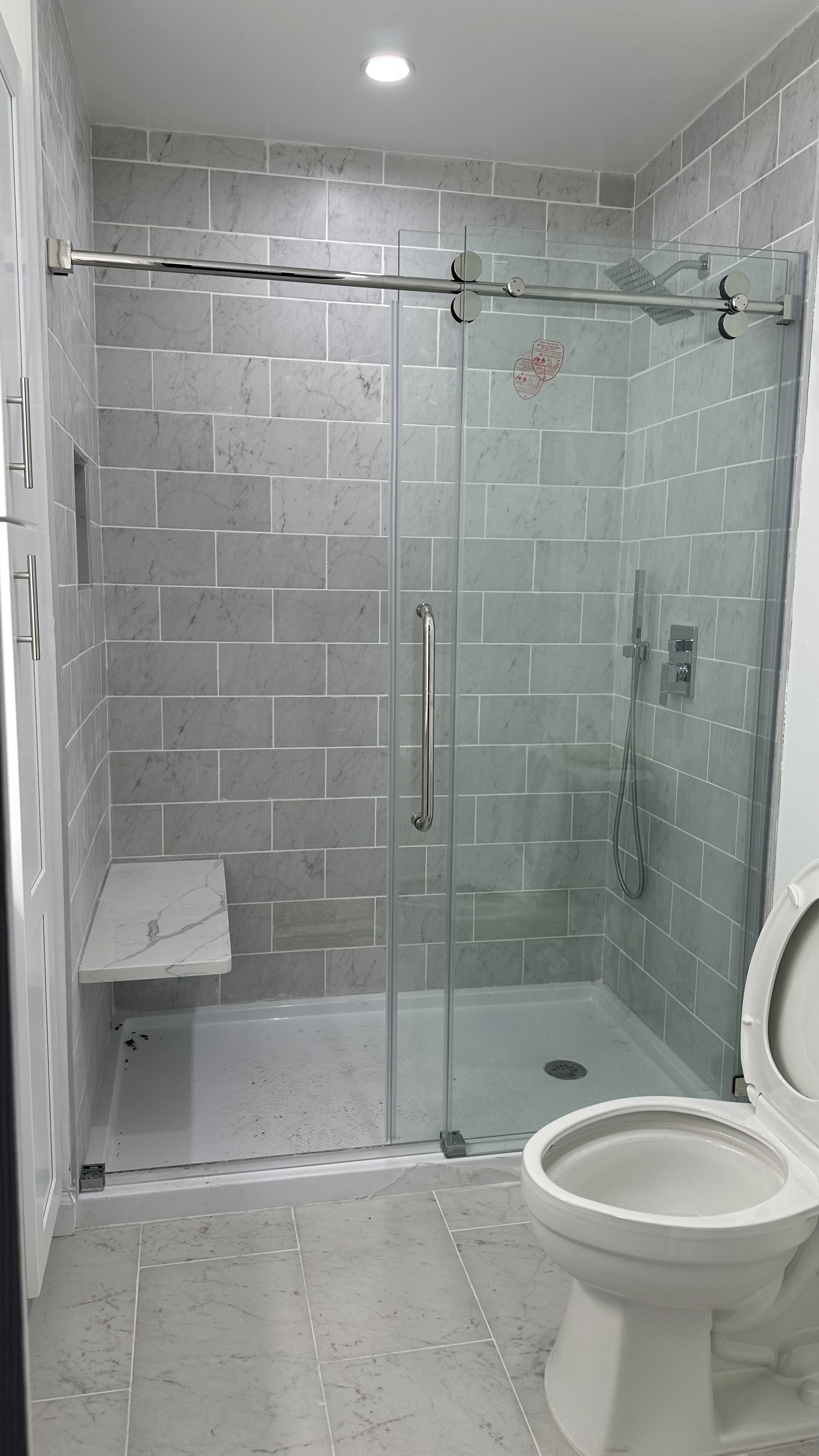 Demolition, tile flooring, wall, light fixture, shower fixtures, toilet, vanity and door installation.