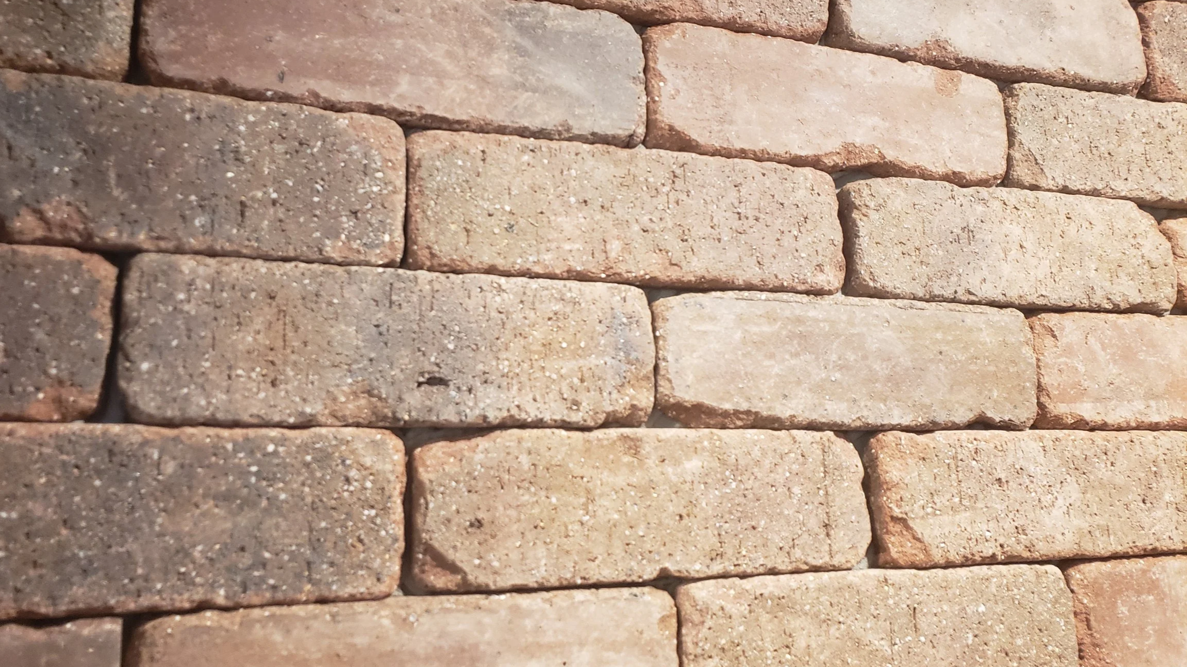 Close-up of a brick wall with reddish-brown bricks arranged in a running bond pattern.
