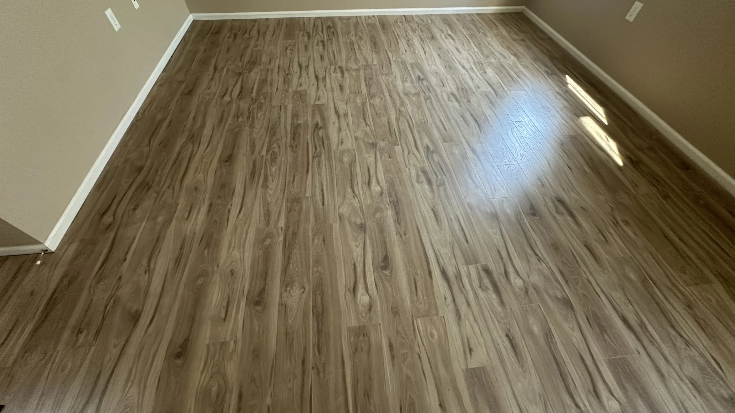 Empty room with beige walls, white baseboards, and hardwood floor.