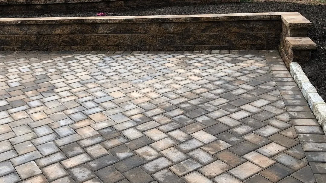 Newly paved brick driveway with a retaining wall and steps to the side