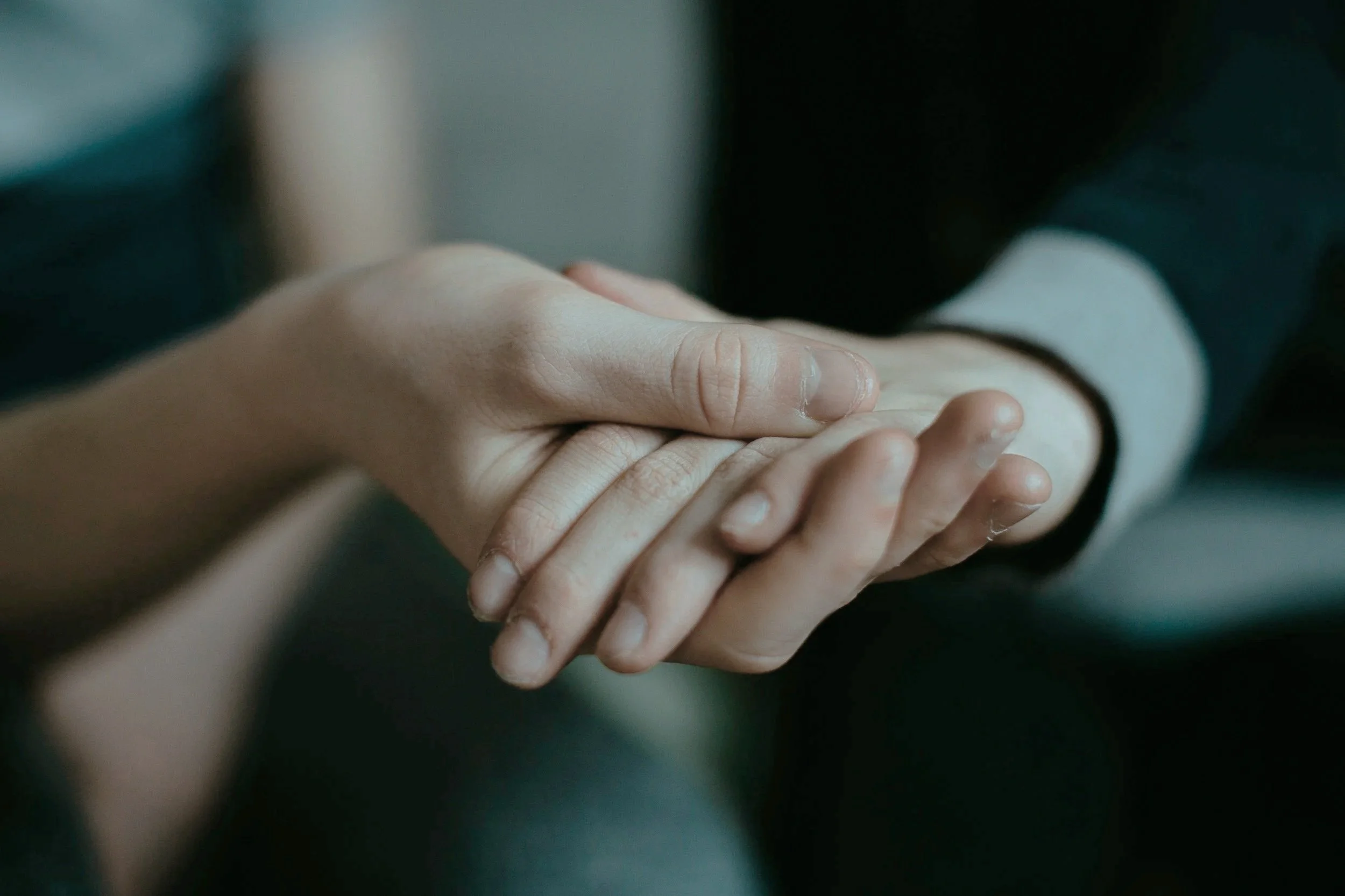 A close-up of two hands gently touching each other.