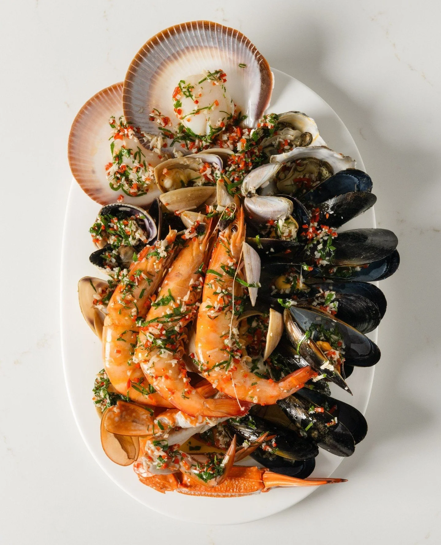 Designed for the centre of the table. Our Hot Shellfish Platter showcases fresh local seafood - blue swimmer crab, prawns, mussels, oysters, scallops, clams and pipis - simply dressed with parsley, chilli, garlic, olive oil and lemon.⁠
⁠
#RickSteinat