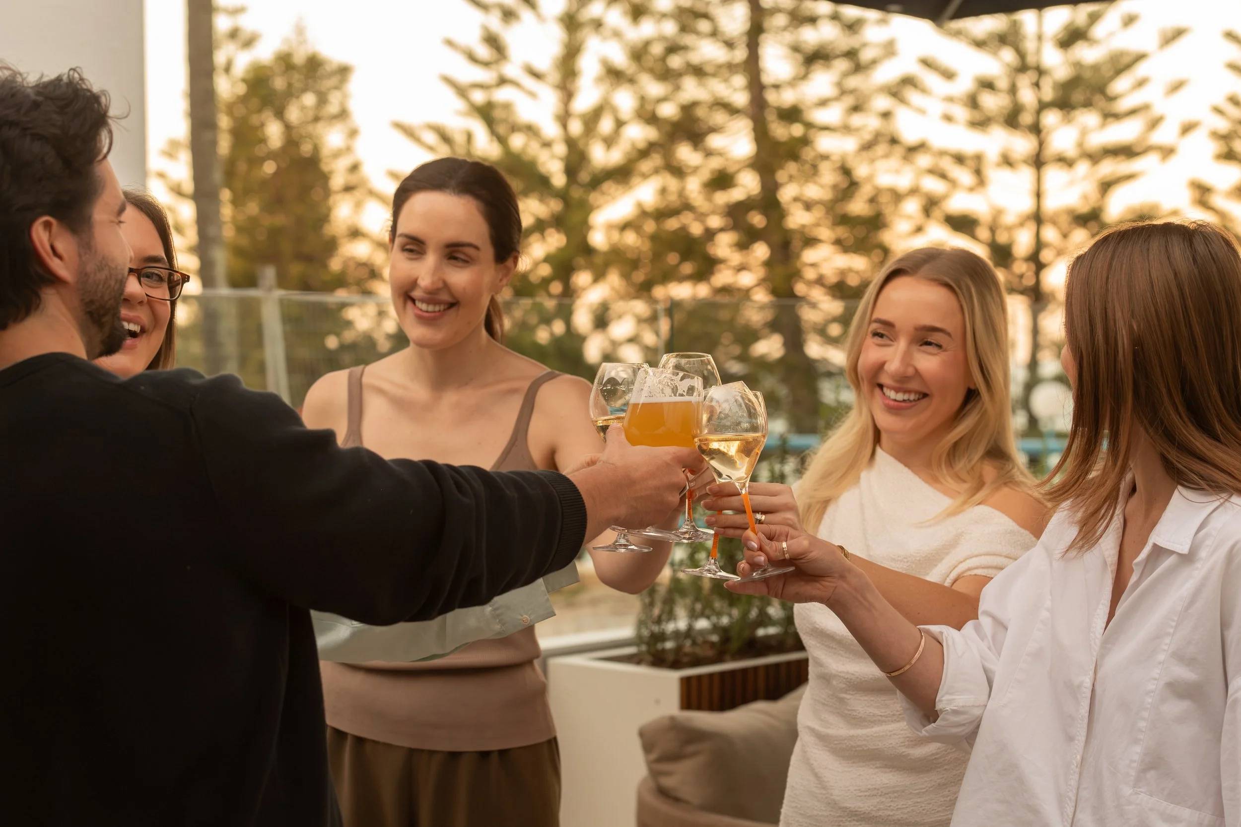 Guests on the Terrace raising a beer and glasses of wine at sunset
