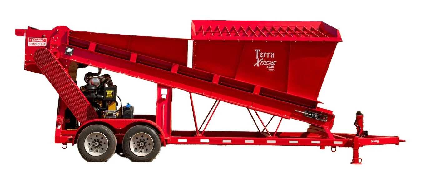 Red hydraulic trailer with a large open-top container labeled 'Terra Xtreme 4240' and a mechanical component at the front, used for transporting and dumping bulk materials.