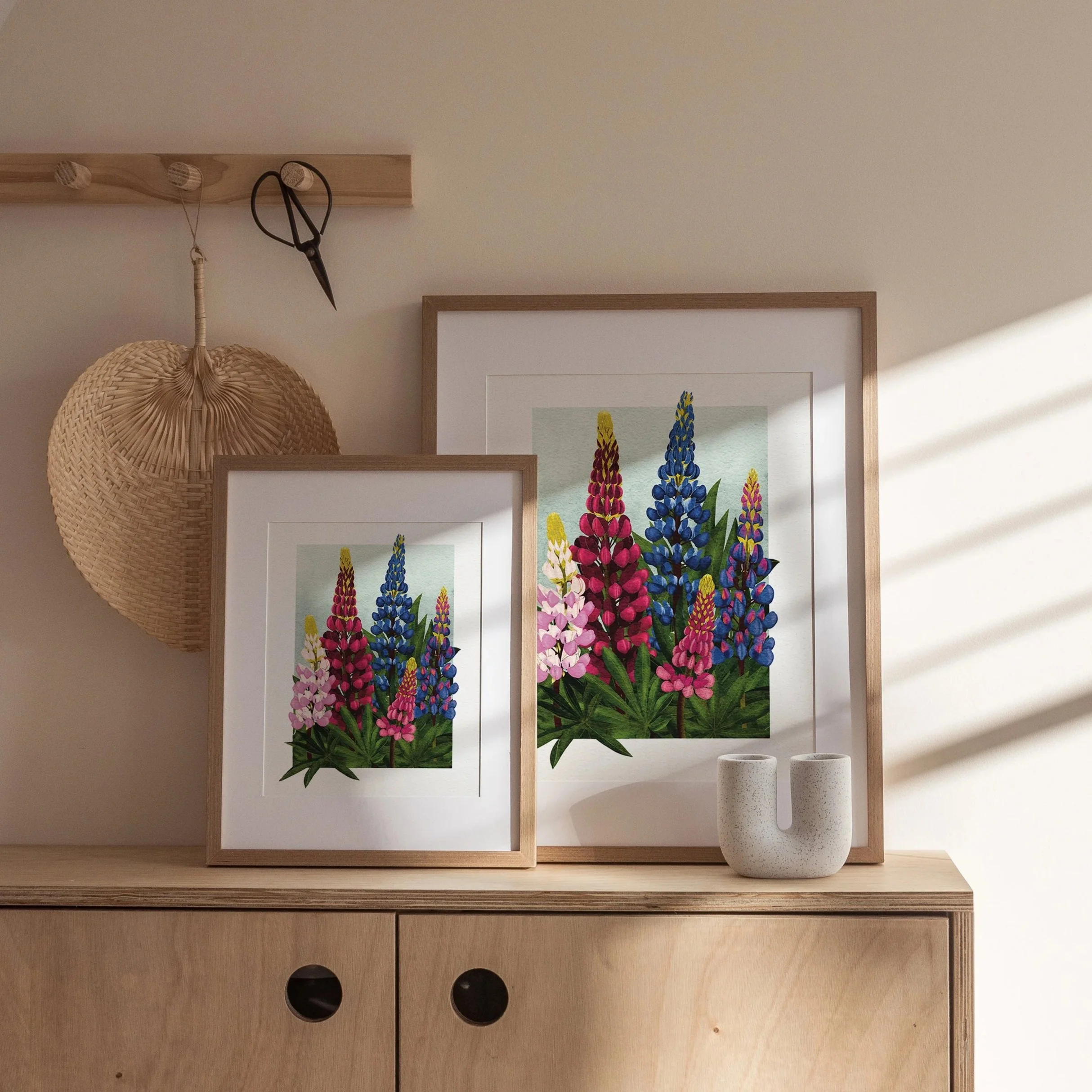 Pair of Lupins art prints framed in white and light wood, displayed on a wooden cabinet with neutral styling, botanical wall décor by Liz Govier Art Studio.