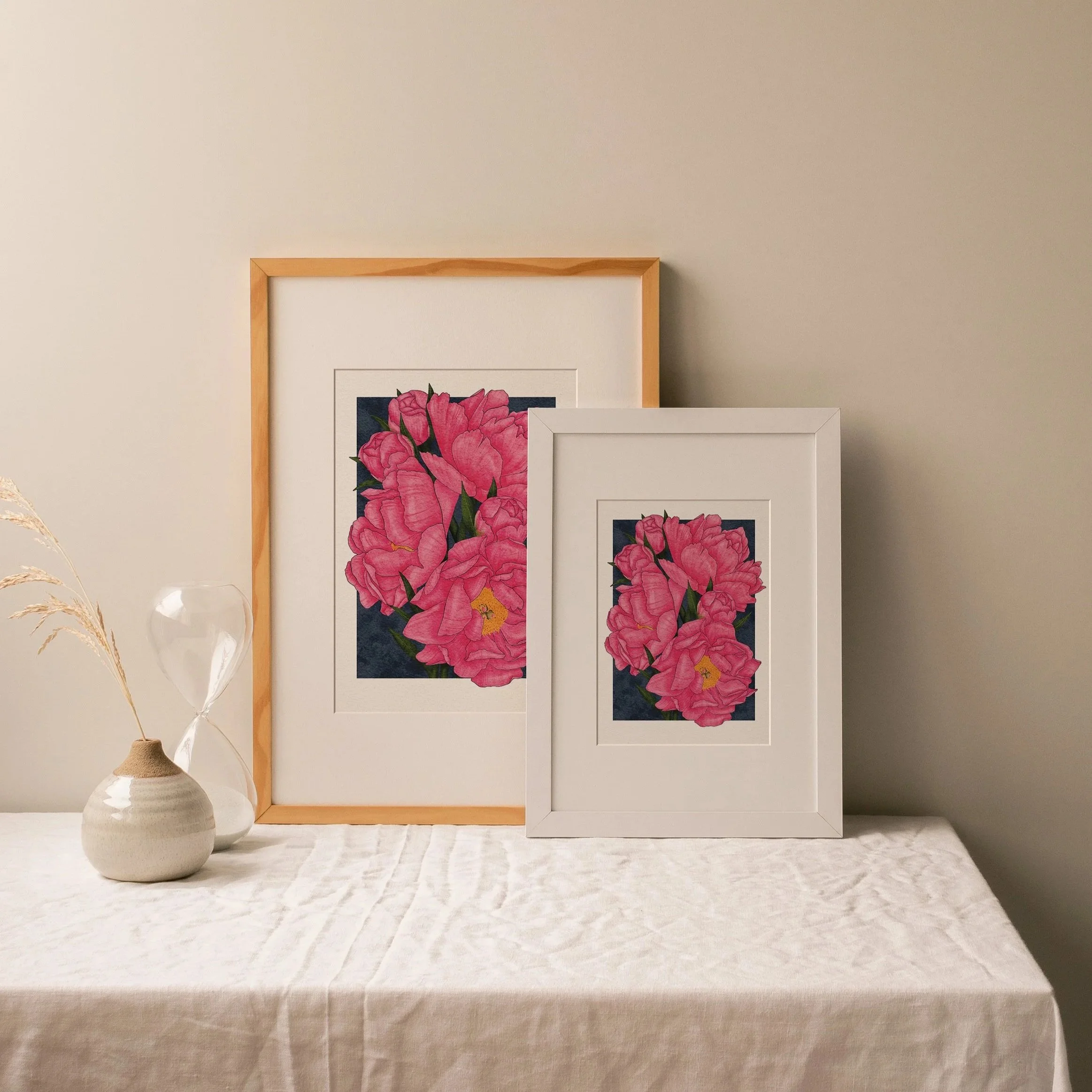 Karl Rosenfield Peonies art prints in two sizes, framed in white and light wood, styled with neutral décor on a linen-covered table.