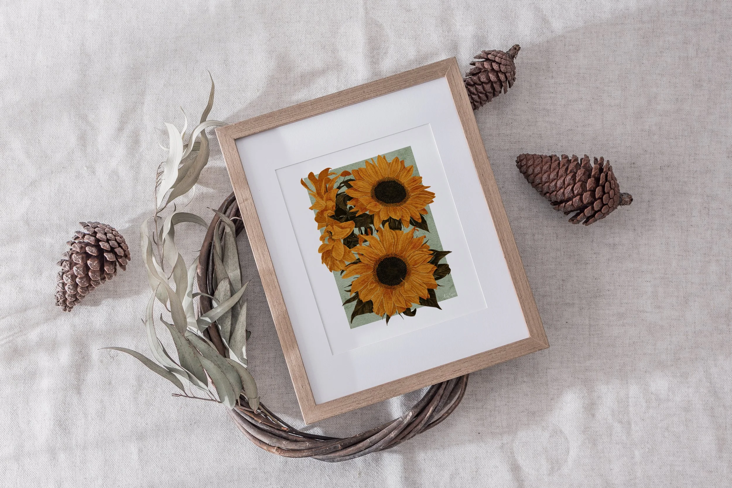 Framed Sunflowers fine art print by Liz Govier Studio surrounded by pinecones and dried foliage in soft natural light.