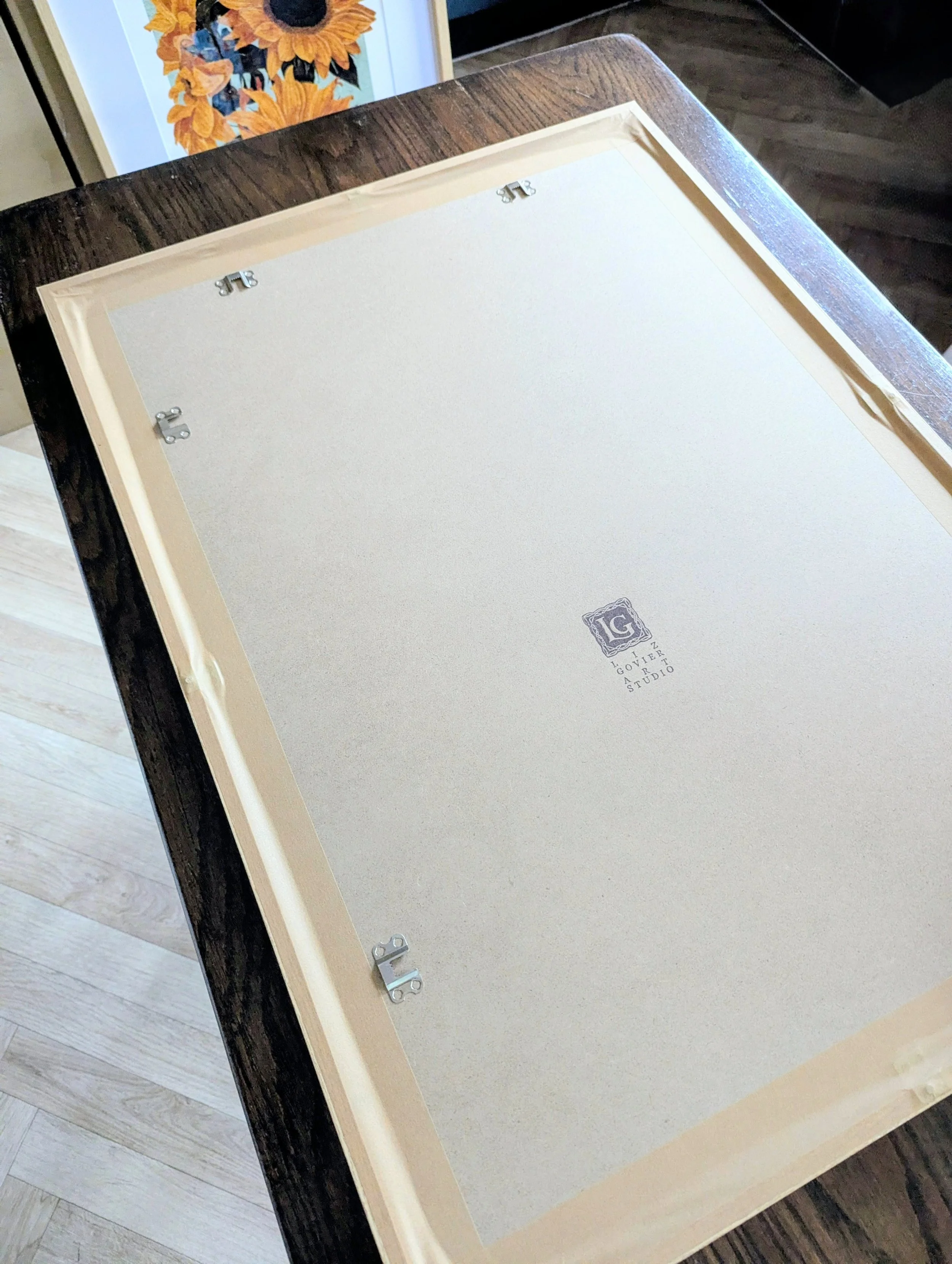 Close-up of a botanical print being framed and prepared for transport.