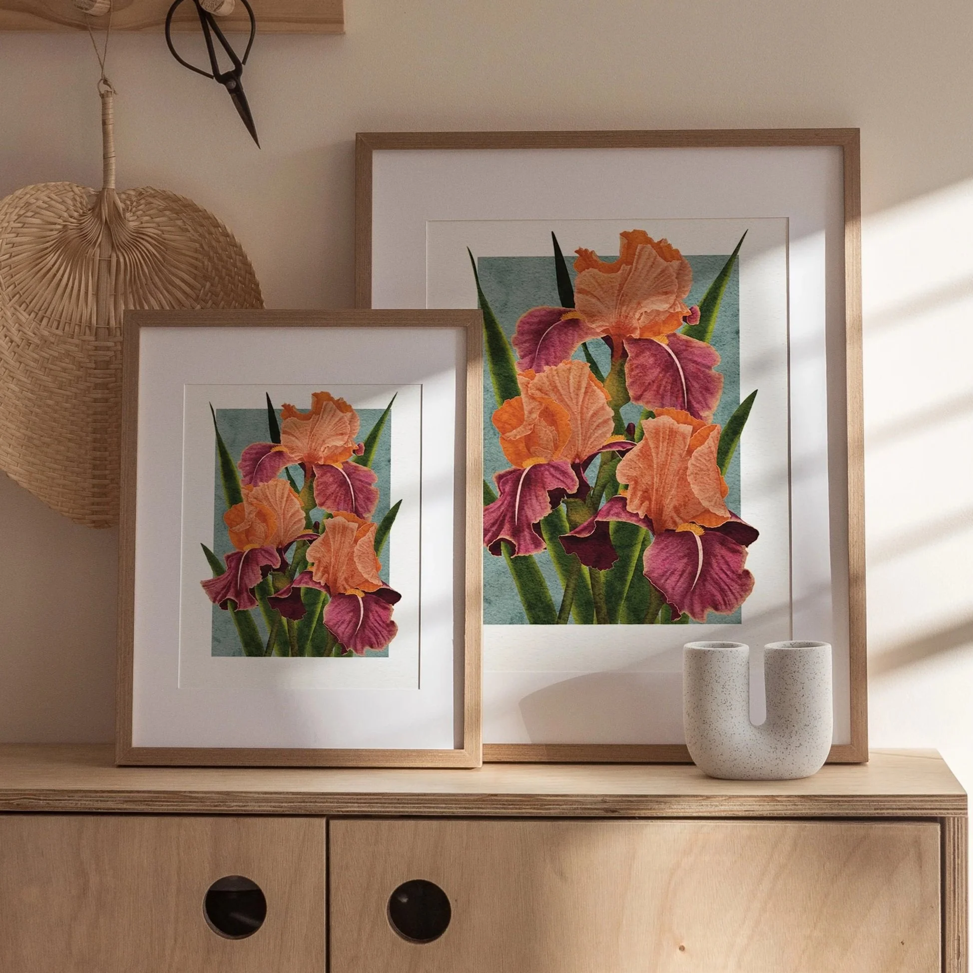 Two sizes of Carnaby Iris art prints framed in white and light wood, styled together on a wooden cabinet with ceramic vase, fine art botanical illustration by Liz Govier Art Studio.