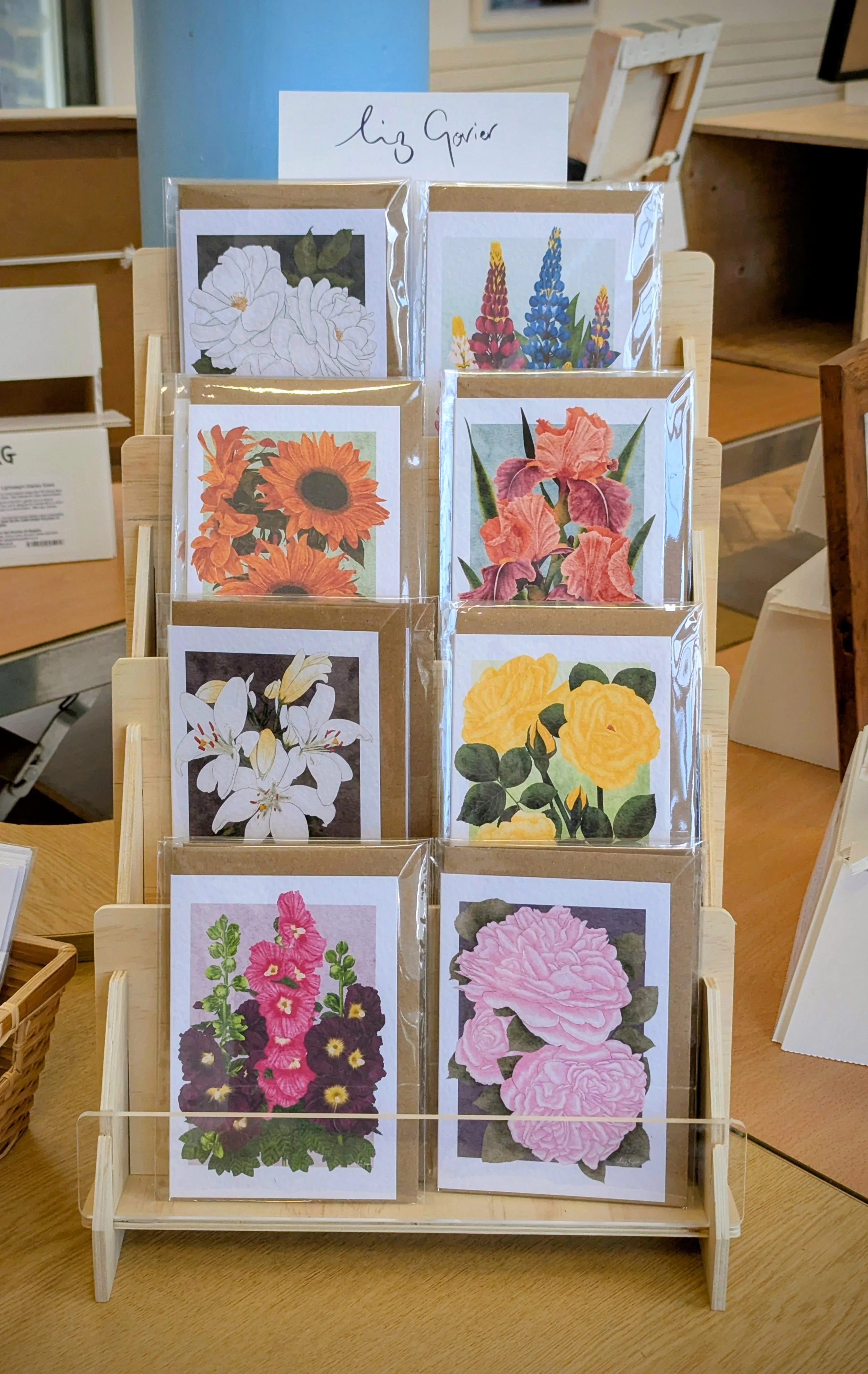 Botanical greeting cards displayed on a wooden desk, featuring floral illustrations.