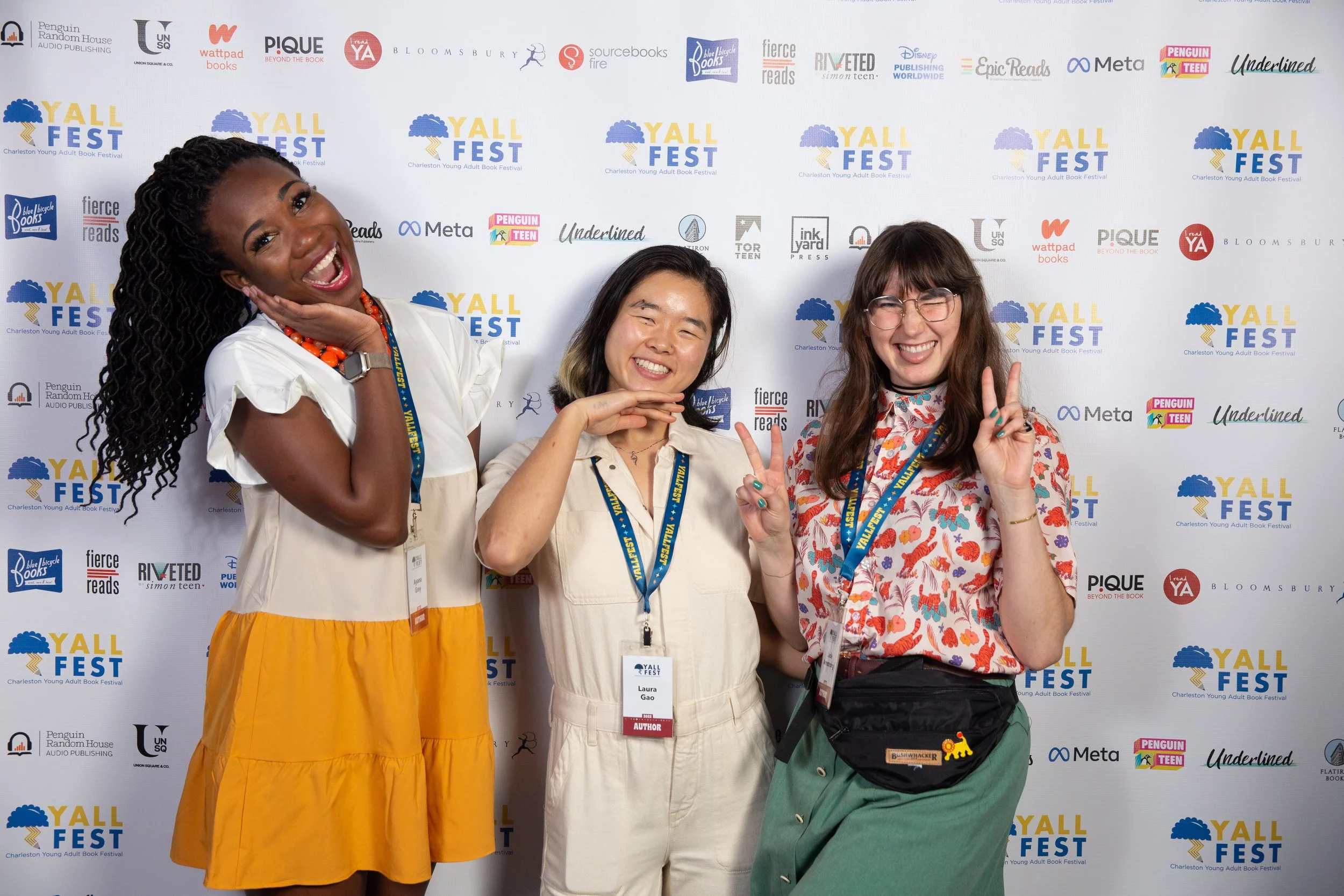 Authors Ayana Gray, Laura Gao, and Jade Armstrong pose in front of the step and repeat