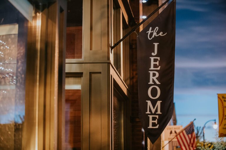 Black vertical banner with white text reading 'the JEROME' hanging outside a building at dusk.
