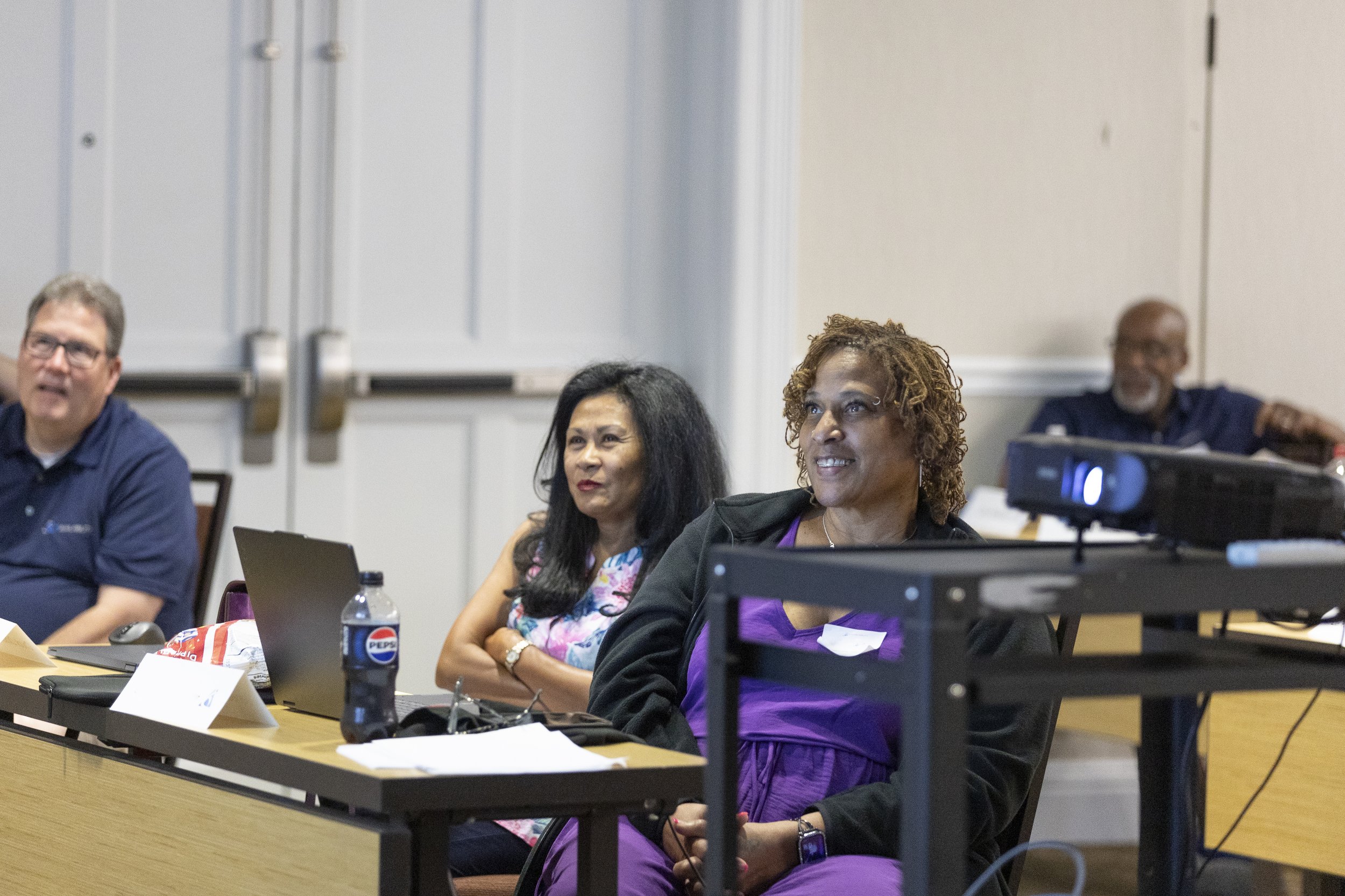 Four people sitting at a conference table during a meeting or presentation.