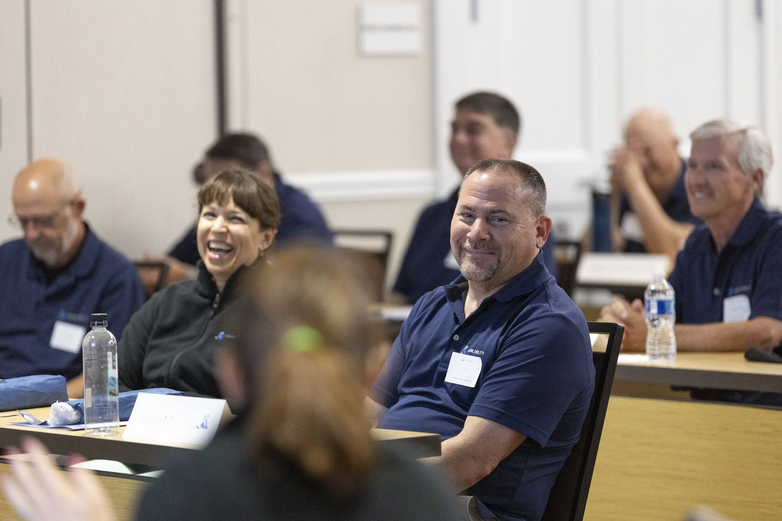 People sitting at a conference table, smiling, and engaging in a discussion.