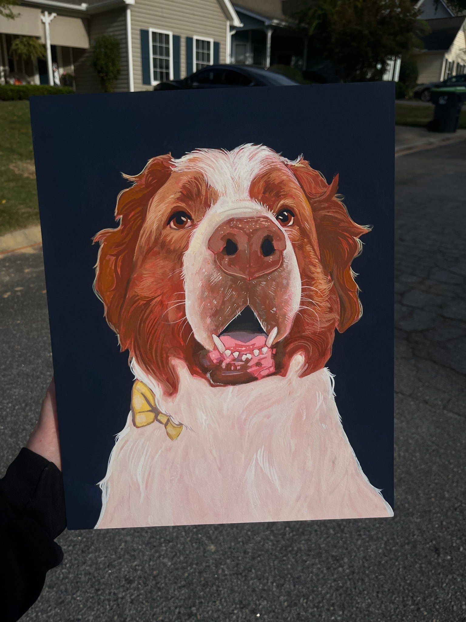 A painting of a happy brown and white dog with a yellow bow tie, showing its tongue and teeth, on a dark background.