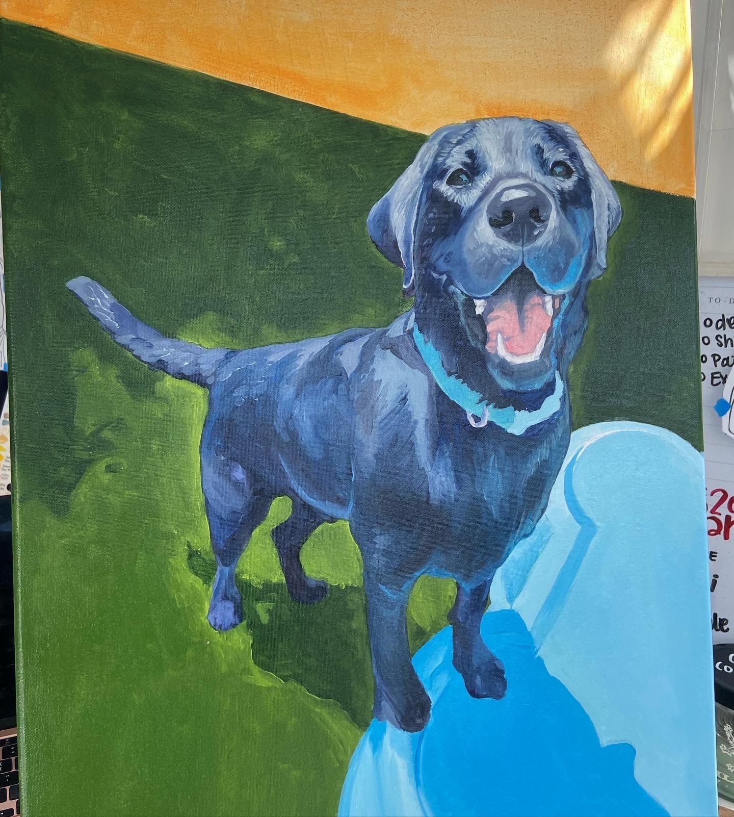 A painting of a happy black Labrador retriever dog with its mouth open, standing on a blue surface against a green background with an orange section at the top.