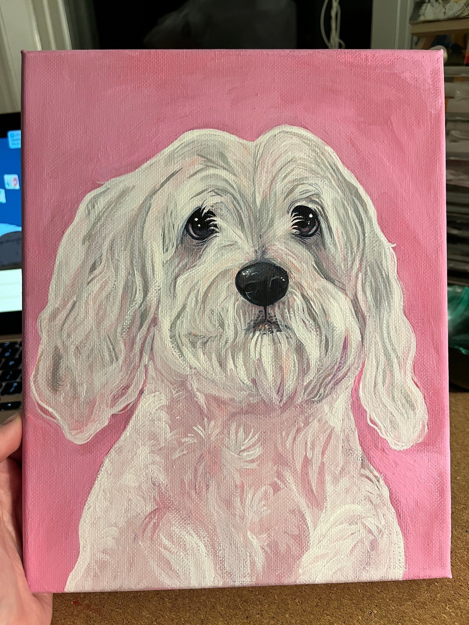 Painting of a white fluffy dog with long ears and dark eyes against a pink background.
