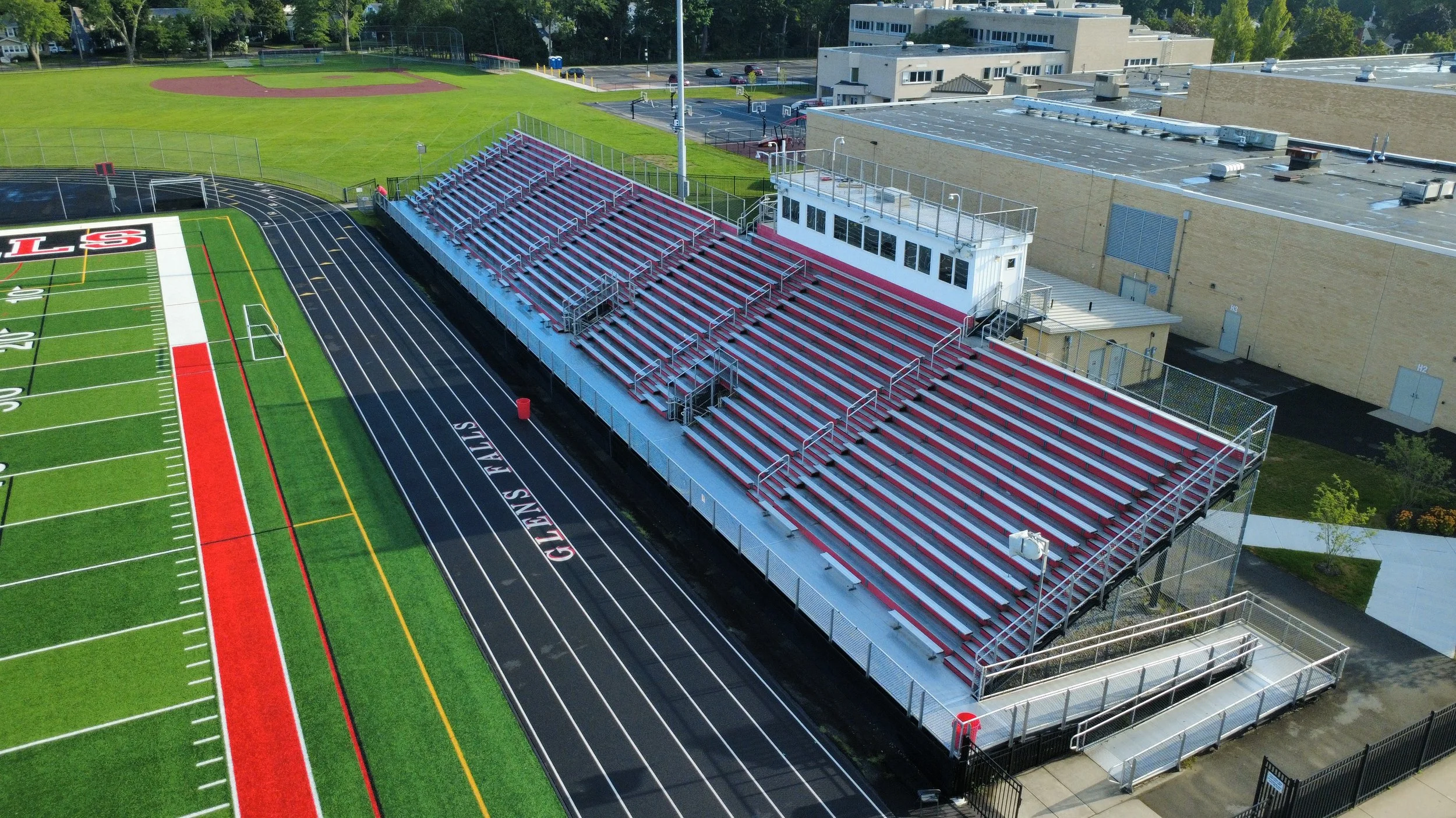 Aerial view of a high school football stadium with bleachers, football field, and surrounding buildings and roads.