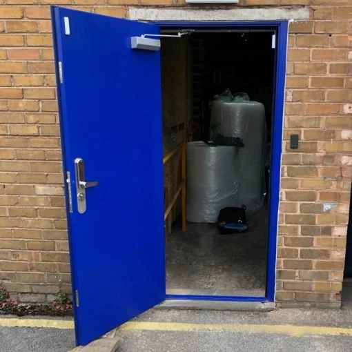 Open blue door leading into a storage room with large wrapped objects inside.