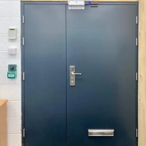 Blue double doors with a mail slot and various security devices mounted on the wall beside it.