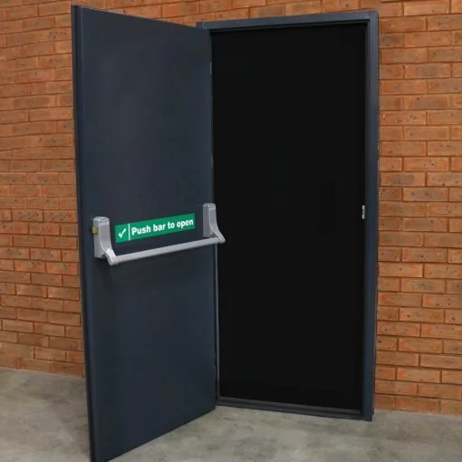 Open black metal door with a green sign that says 'Push bar to open' on a brick wall.