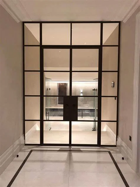 Glass door with a black metal frame separating two indoor spaces in a modern interior.