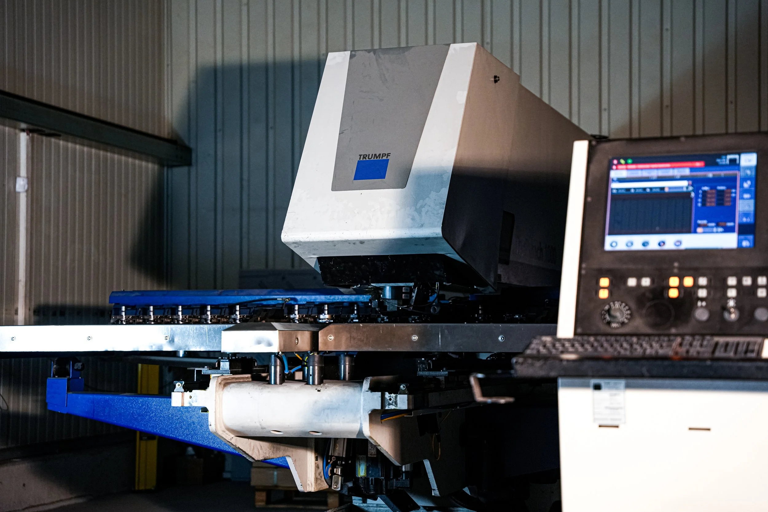 Industrielle Maschine mit einem Computerbildschirm in einer Fabrikumgebung.