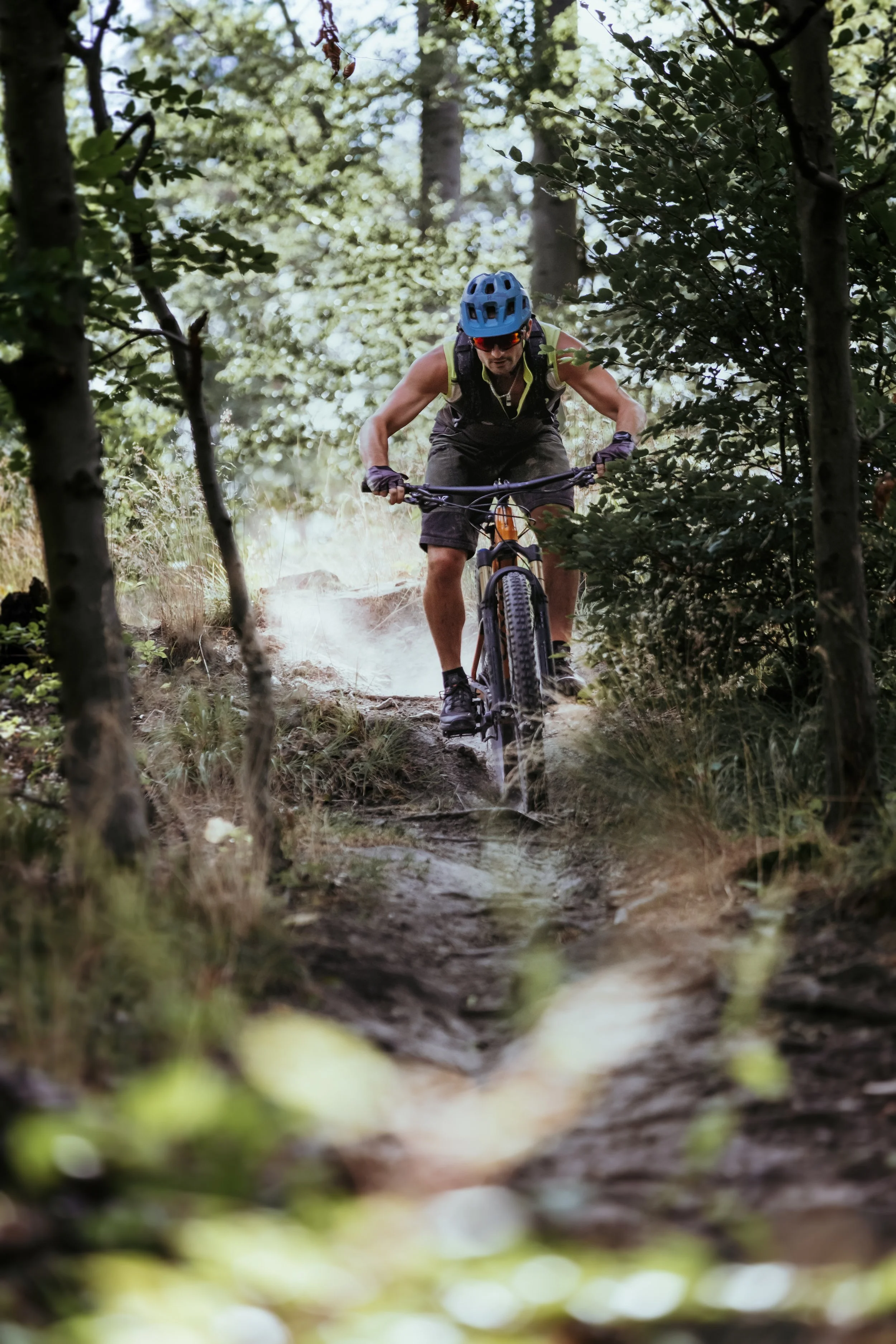 Ein Mountainbike-Fahrer in einem Wald, der einen schmalen, holprigen Pfad hinunterfährt.