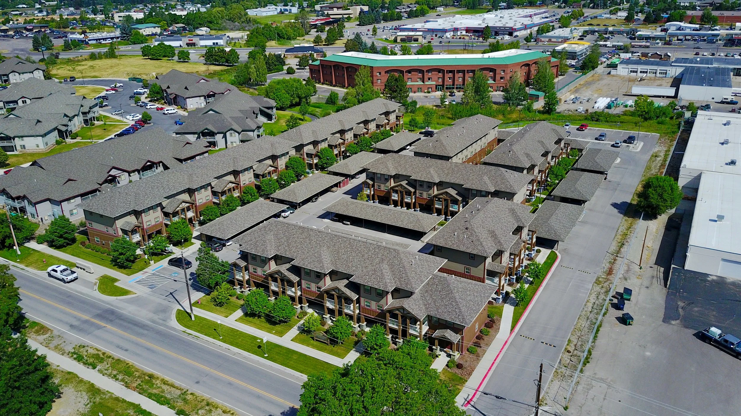 Aerial view of a residential apartment complex with multiple buildings, parking spaces, and surrounding greenery.