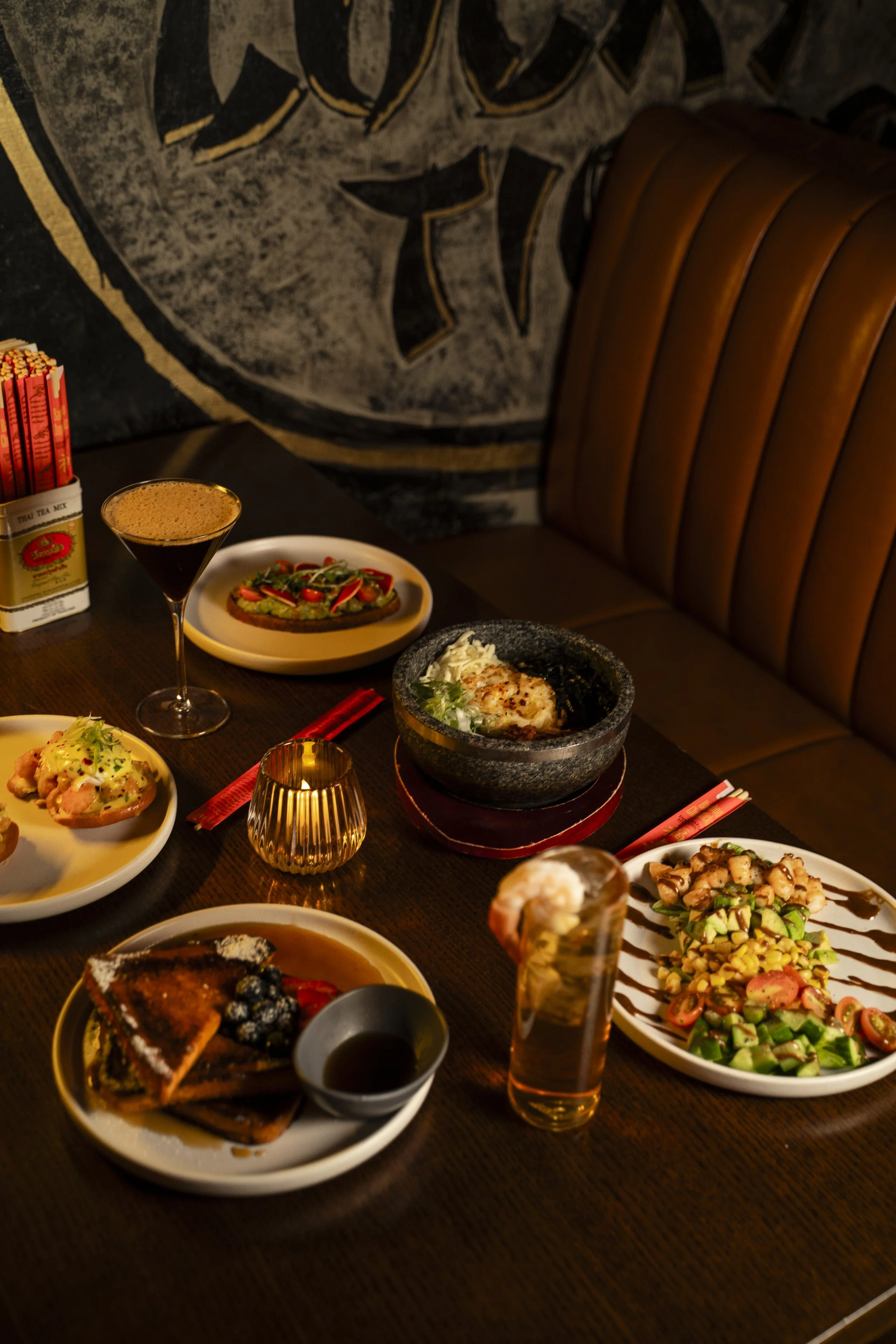 A table set with various dishes including salad, dessert, small appetizers, and beverages in a restaurant to enjoy Asian cuisine.